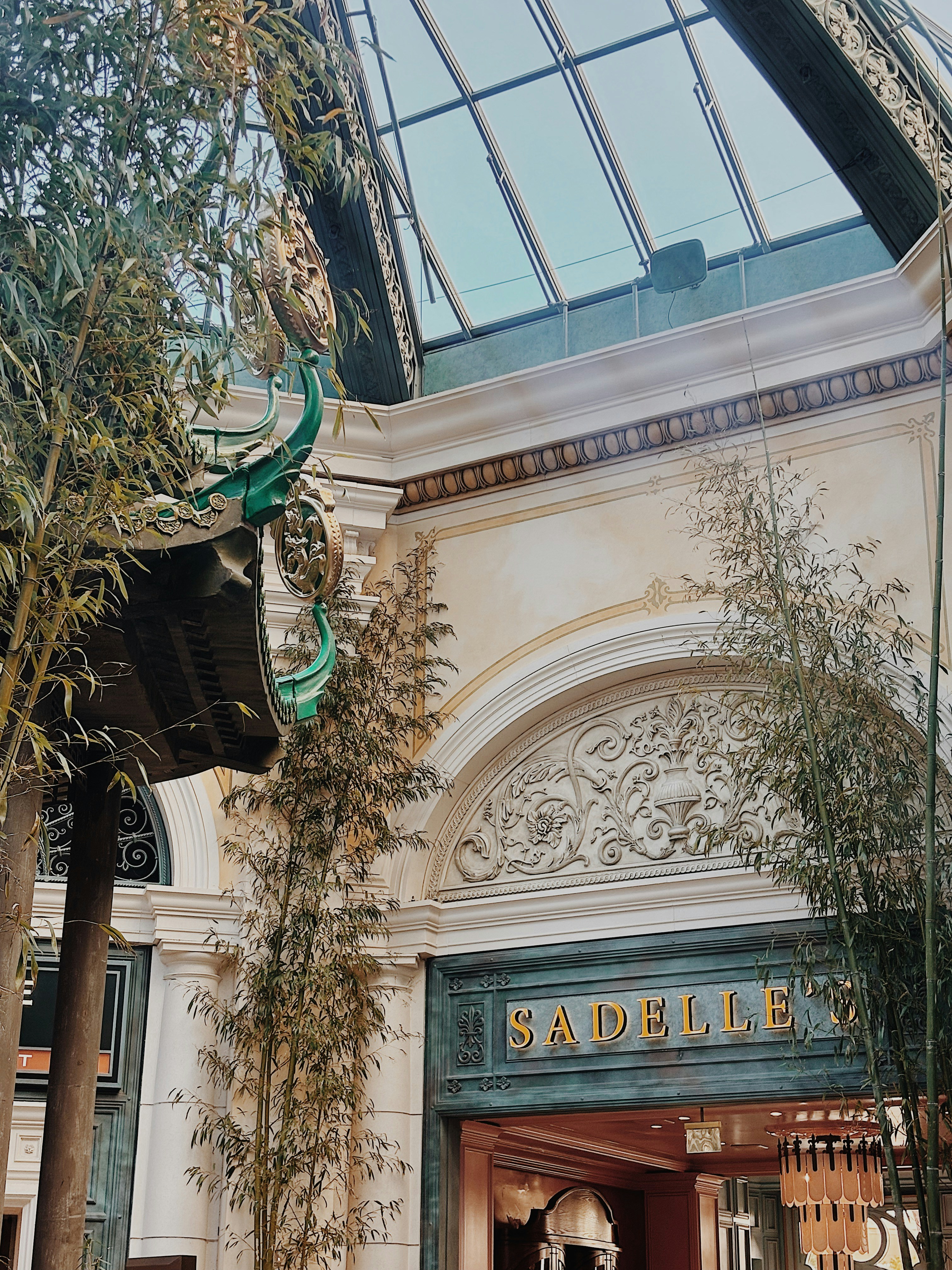 Entrada elegante do prédio com detalhes ornamentados e vegetação.