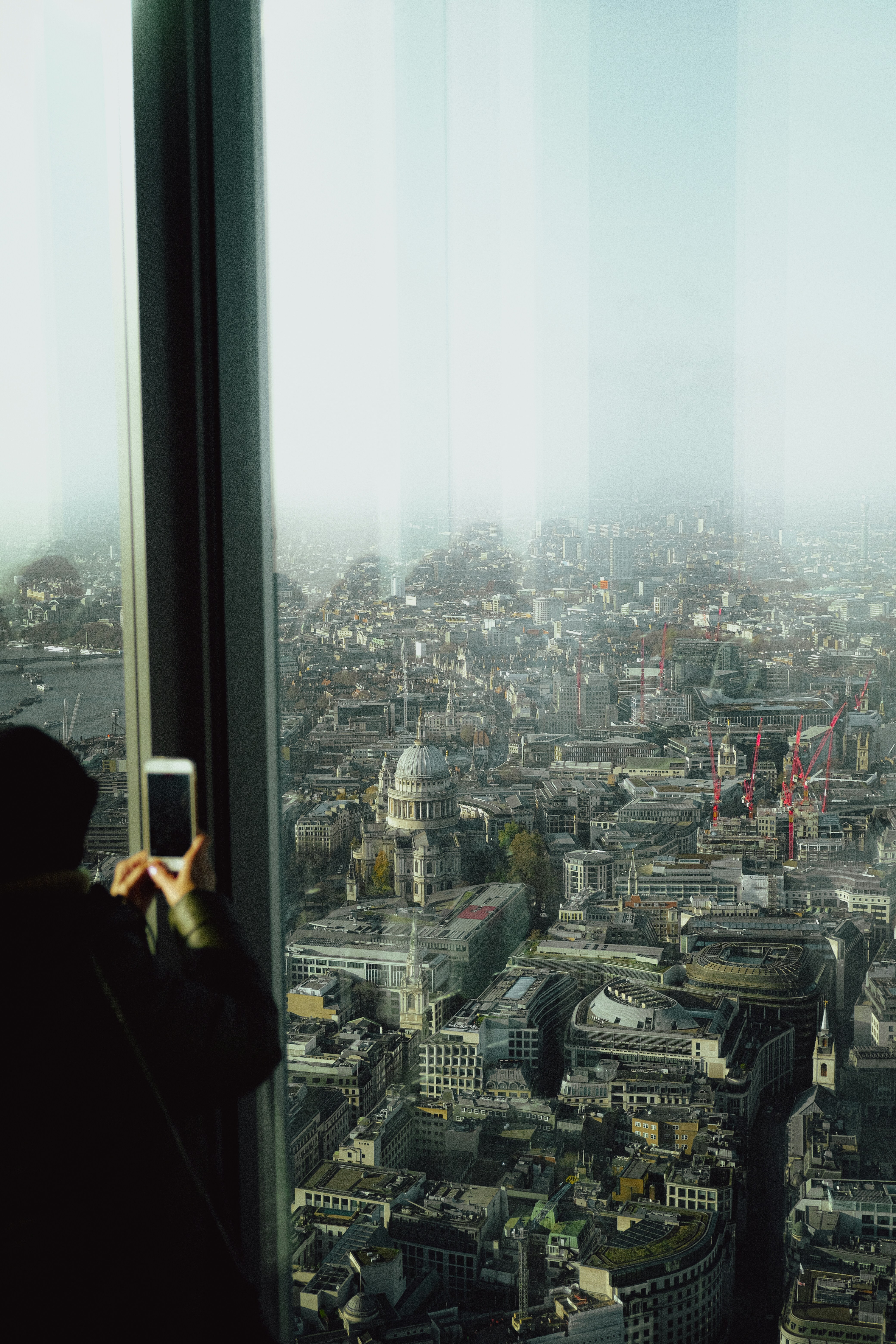 Person macht ein Foto von der nebligen Stadtsilhouette von oben.