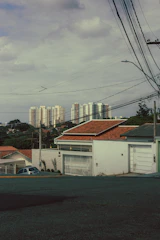 Apartment buildings rise above suburban homes under cloudy sky.