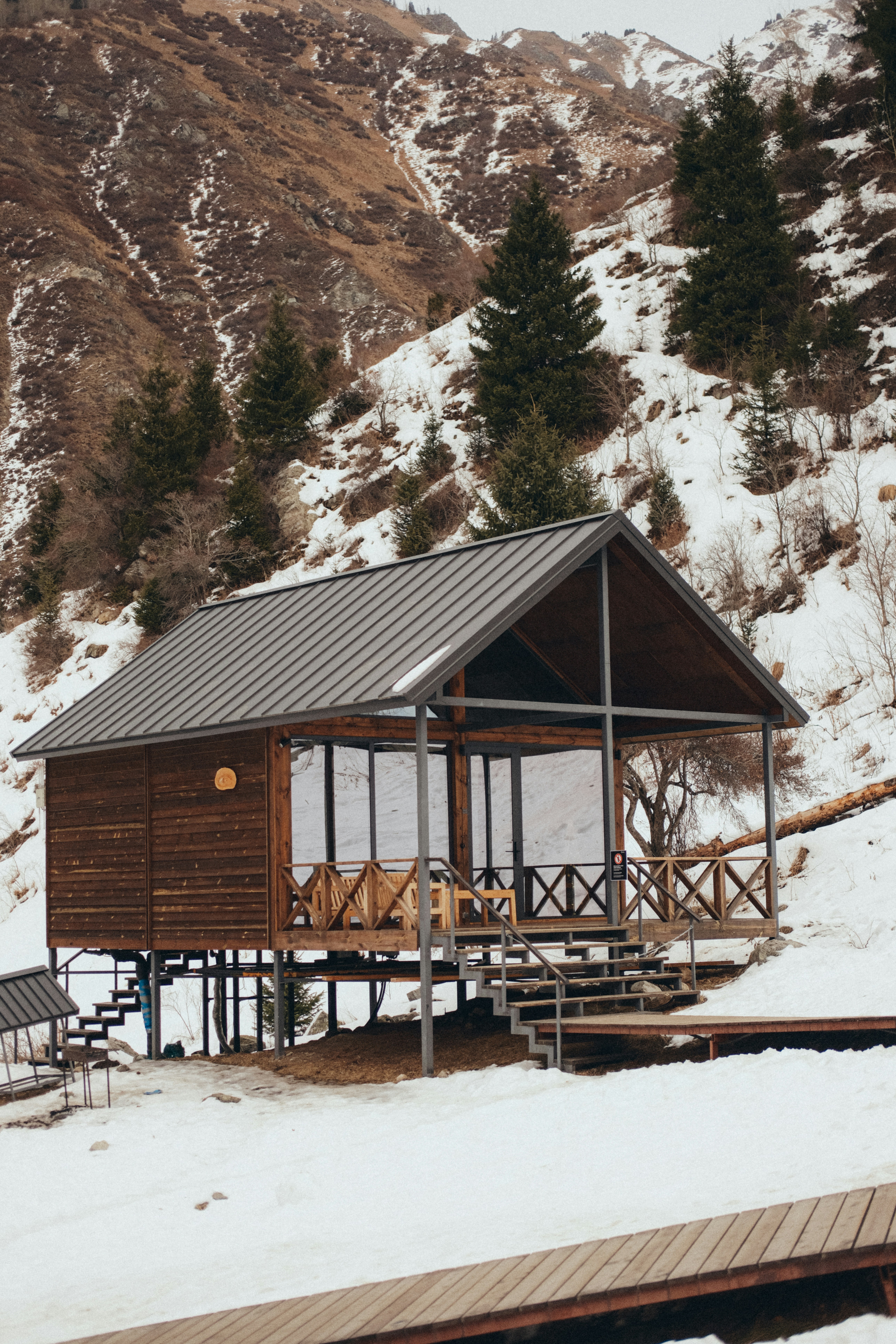 Capanna in legno con grandi finestre in un paesaggio montuoso innevato.