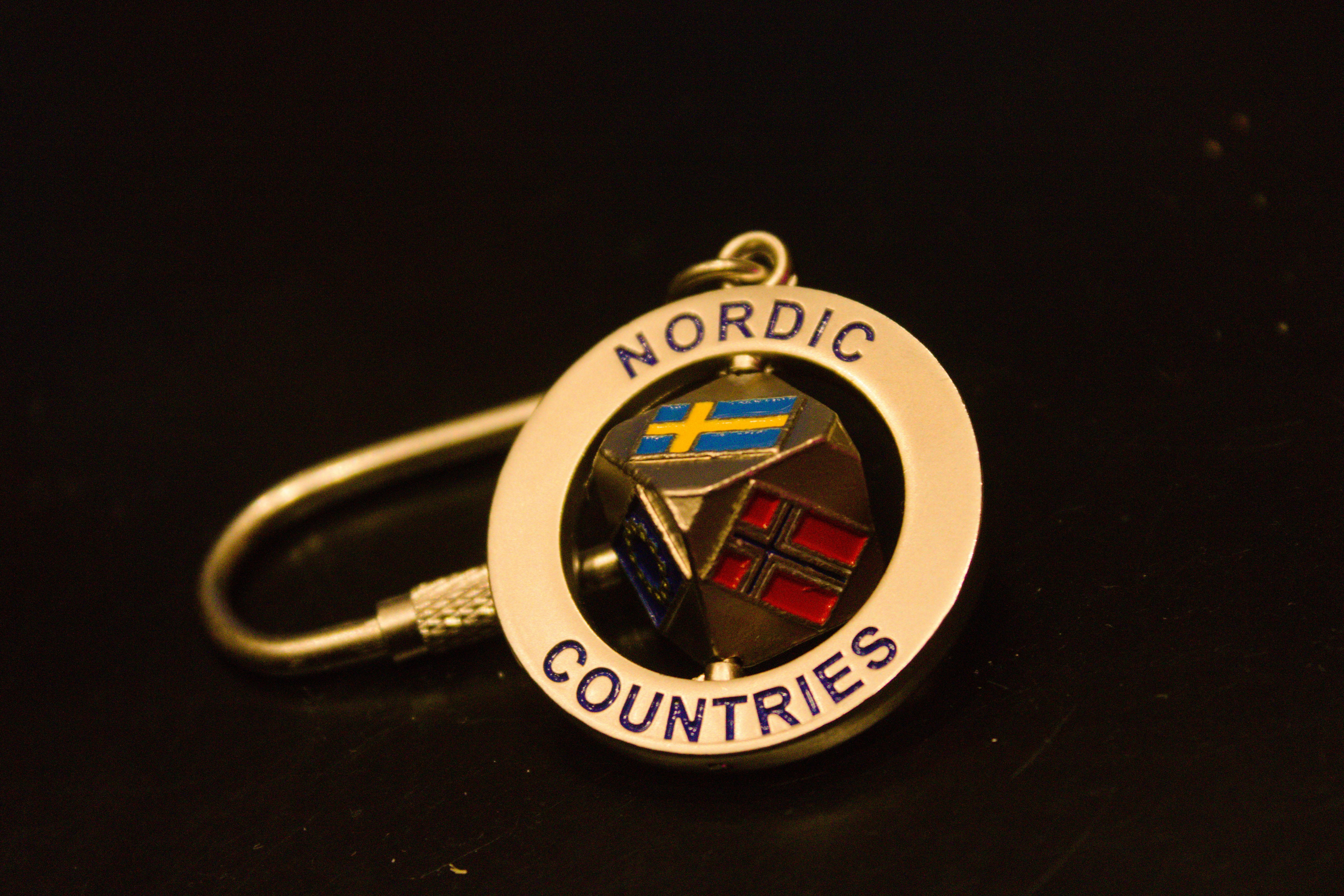A gold keychain with nordic countries flags