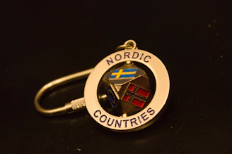 A gold keychain with nordic countries flags
