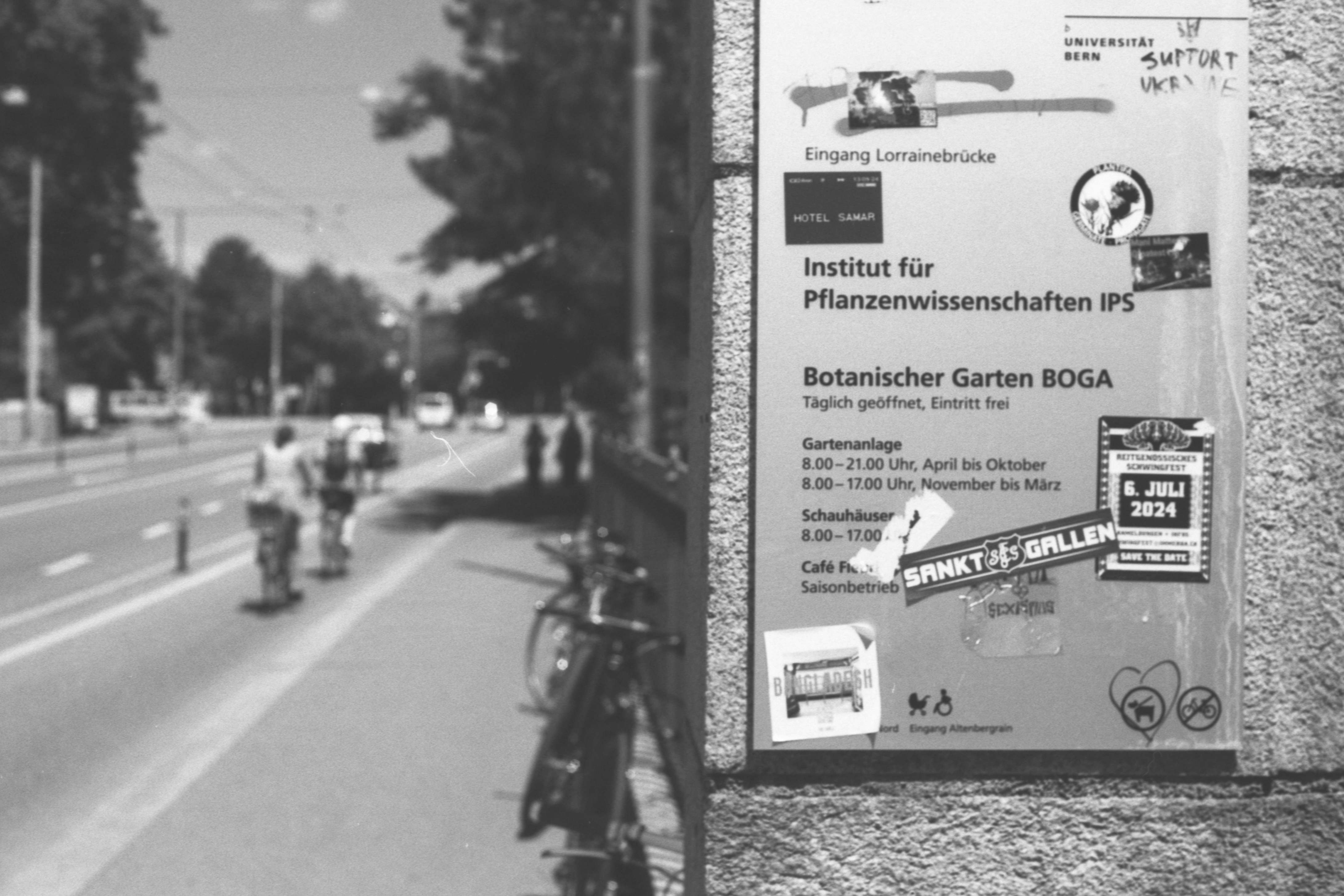 Sign for botanical garden with cyclists on road