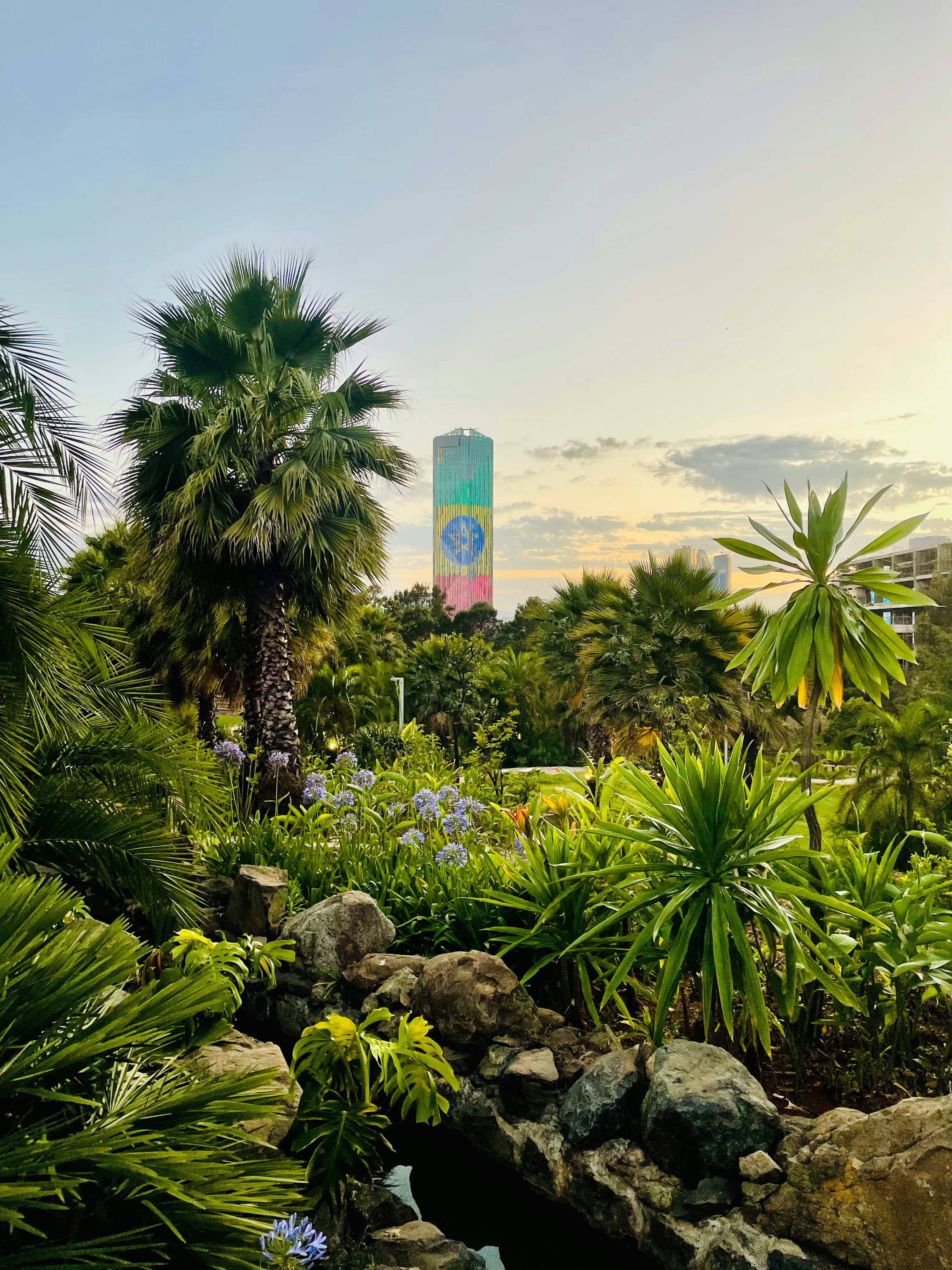 Lush tropical garden with a colorful tower in background.