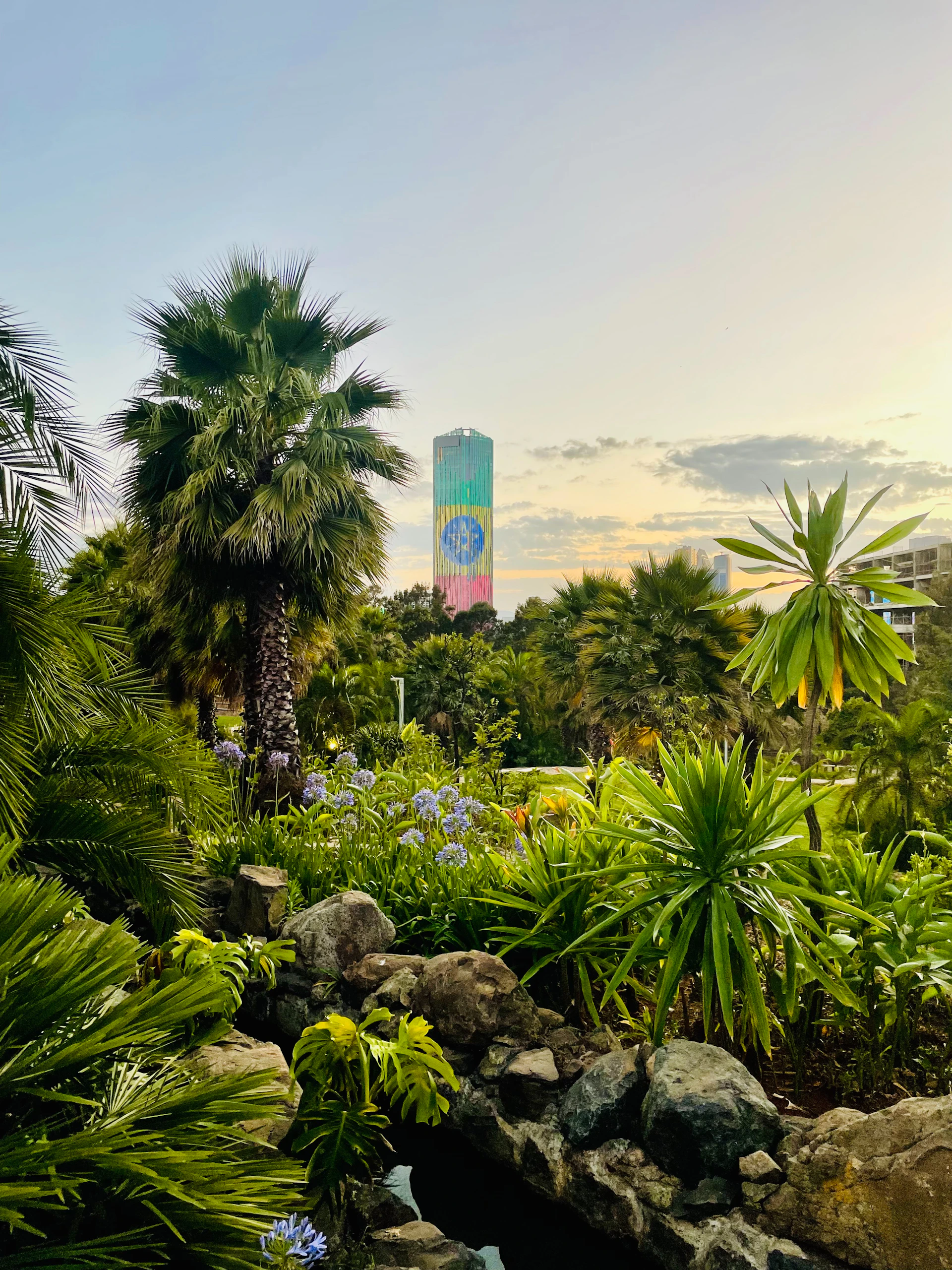 Lush tropical garden with a colorful tower in background