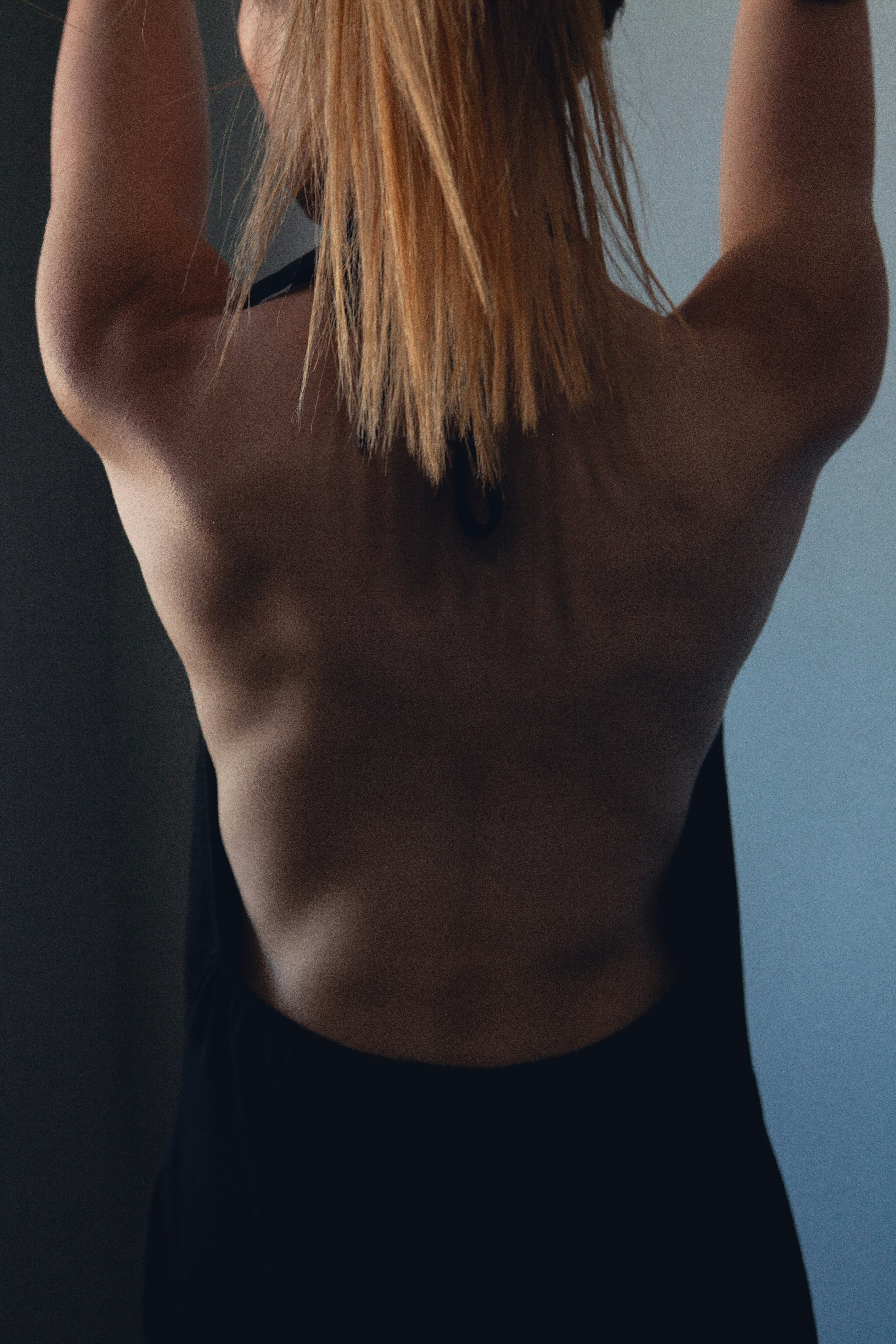 Woman with muscular back holding onto a bar