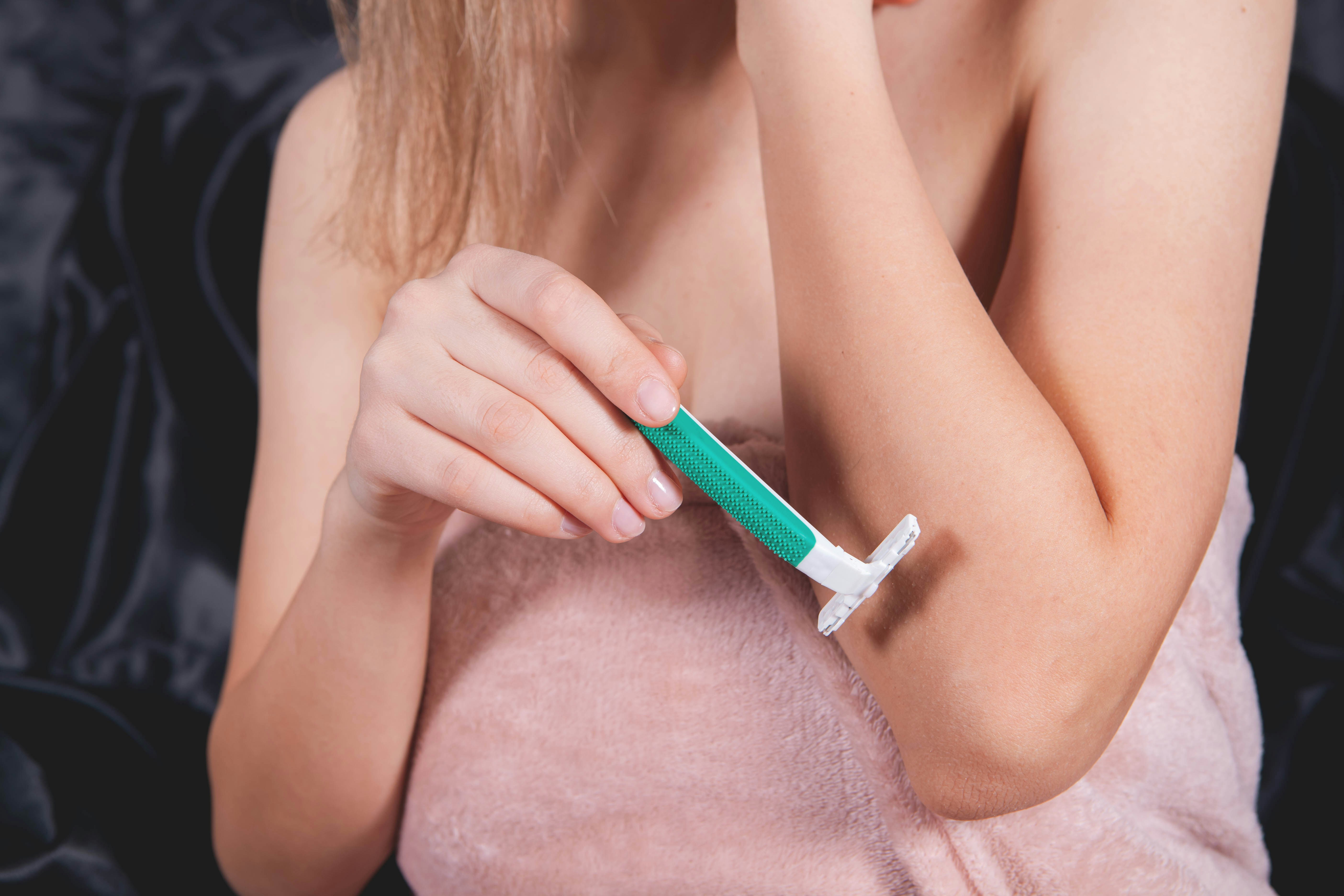Woman shaving her arm with a razor.