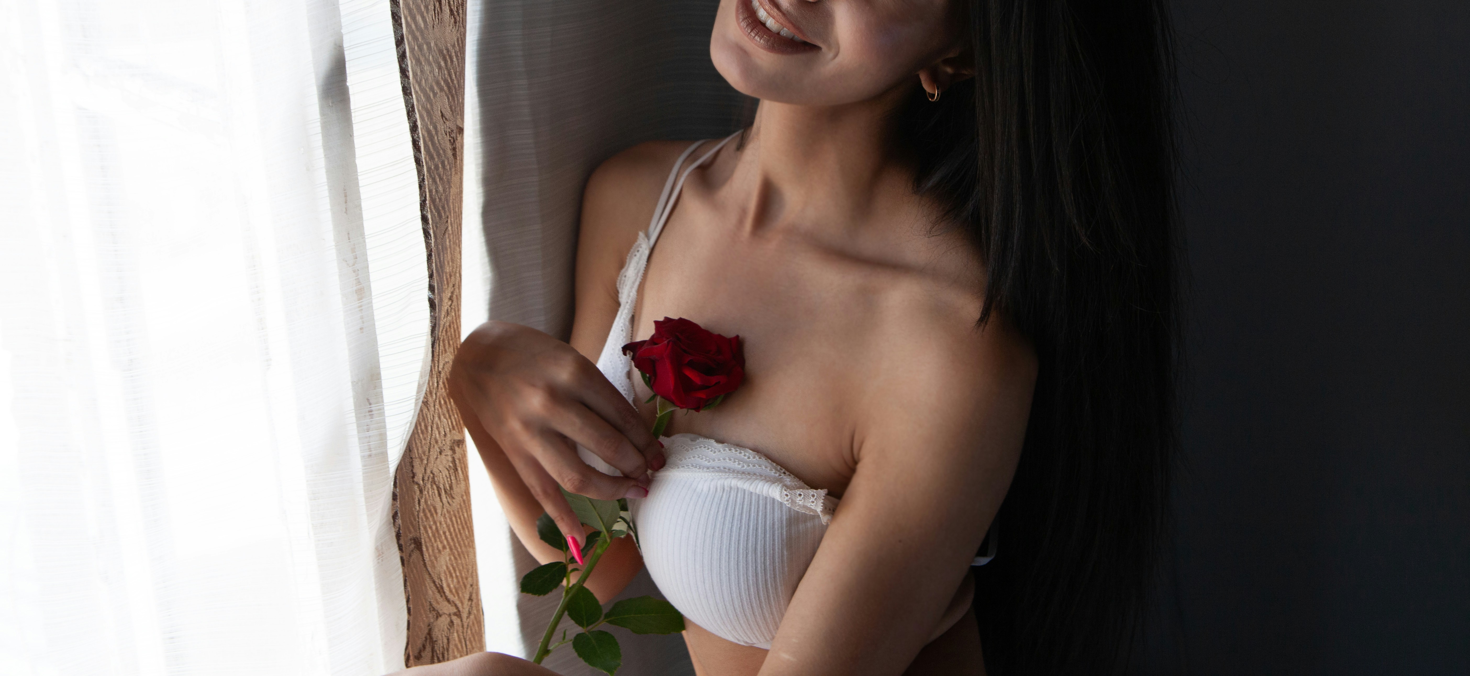 Woman in white bra holding a red rose