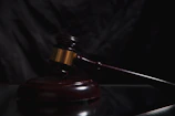 A wooden gavel rests on a dark surface