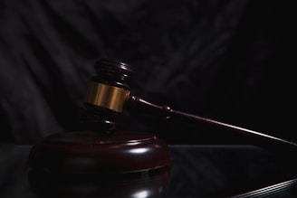 A wooden gavel rests on a dark surface.