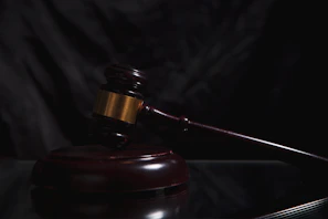 A wooden gavel rests on a dark surface