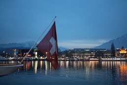 Swiss flag waves over city lights reflected in water