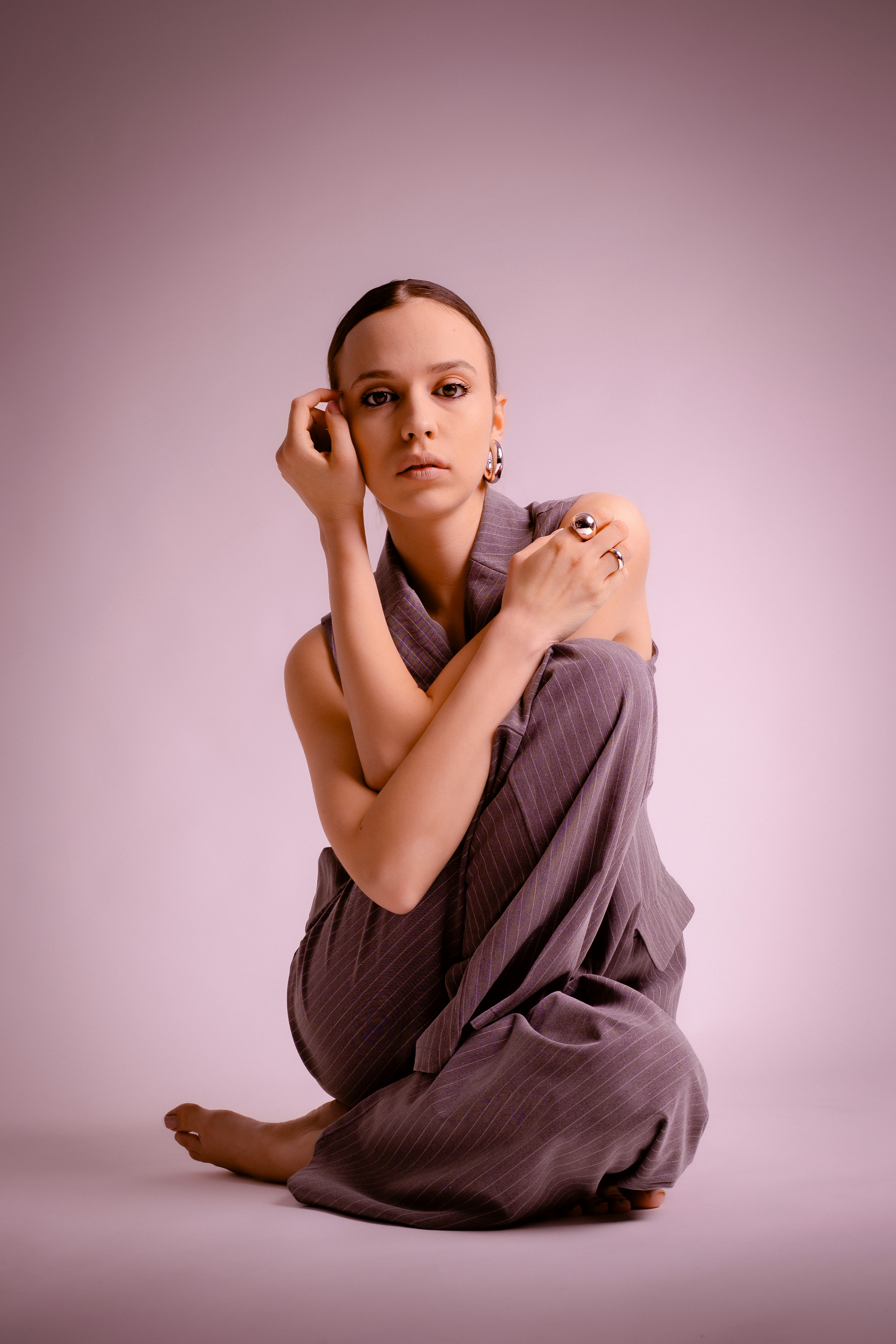 Young woman in pinstripe suit posing against pink background