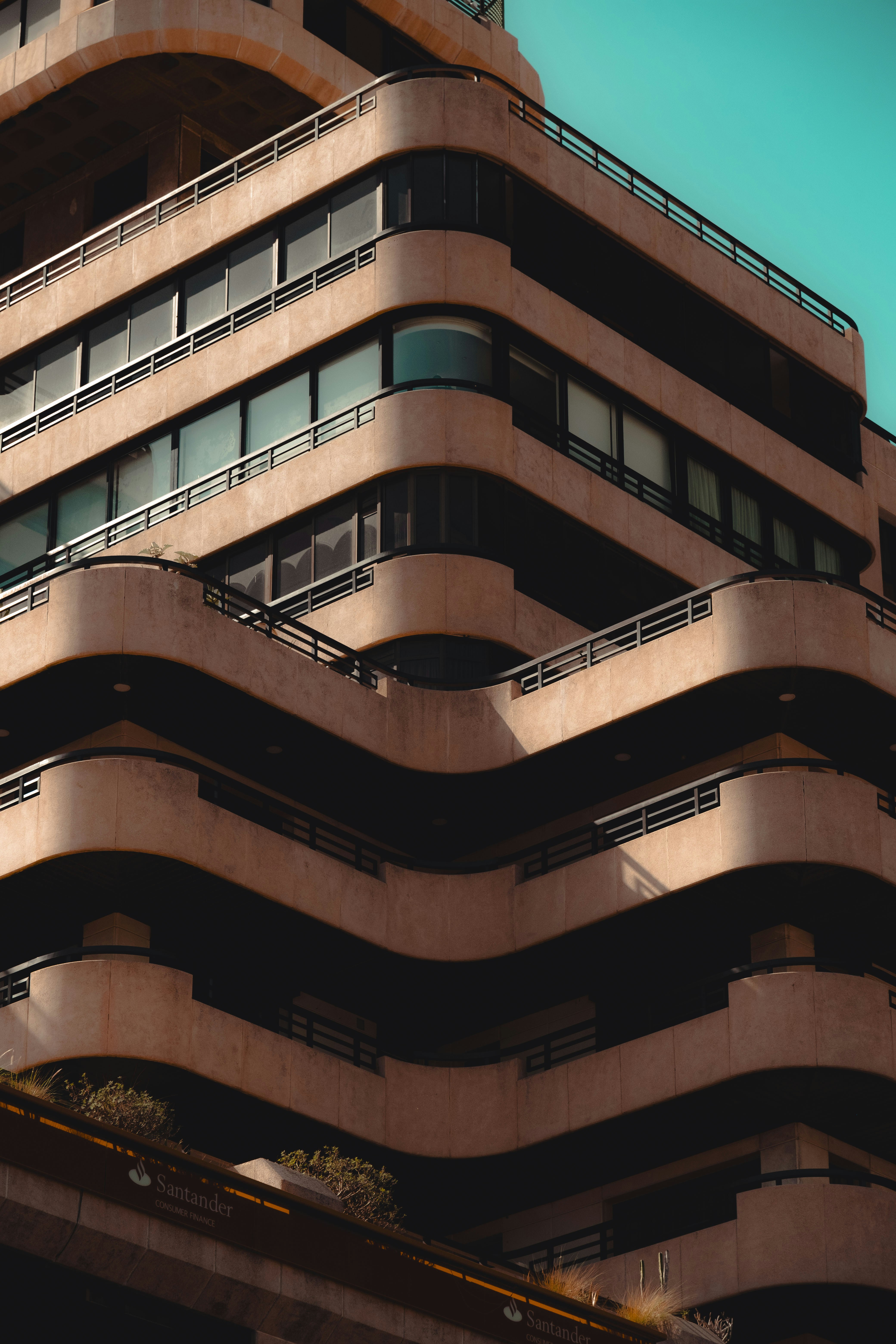 Modern building with curved balconies against a teal sky