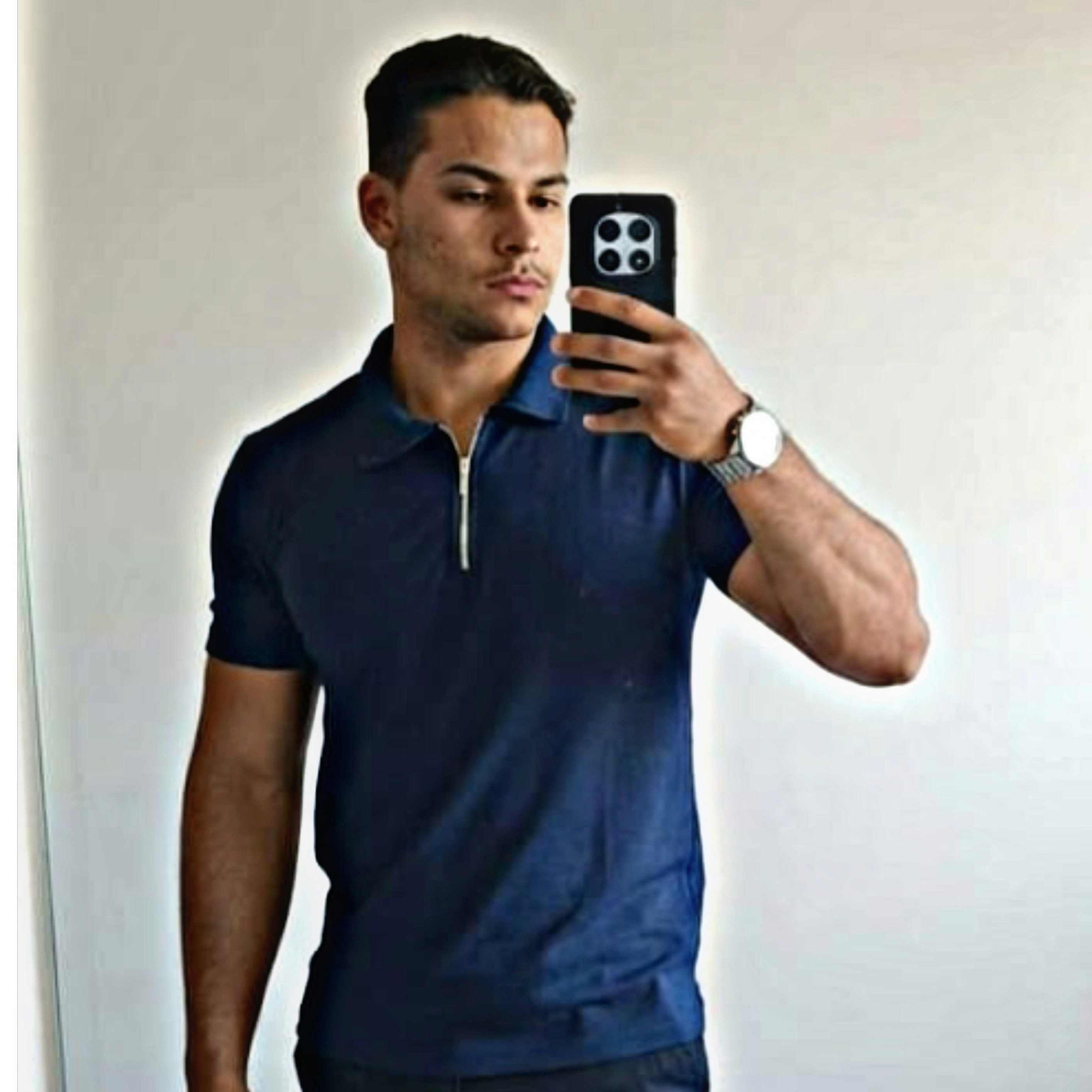 Un homme en polo bleu marine prenant un selfie.