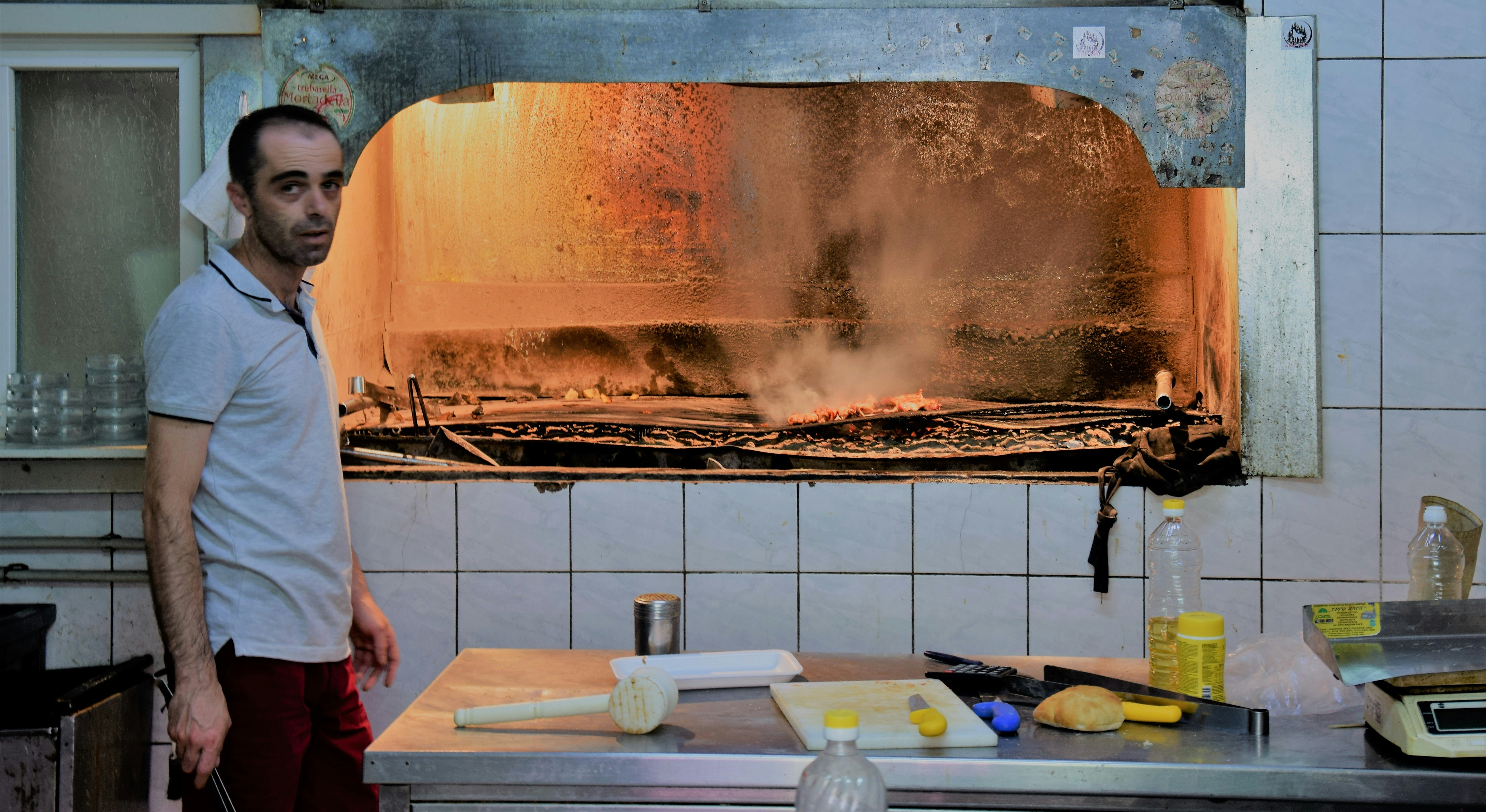 Man standing in a kitchen with a large wood-fired oven