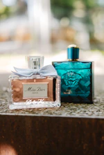 Two perfume bottles on a stone surface.