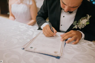 Groom signing marriage certificate with bride beside him