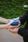 A hand giving a blue gift box to another hand