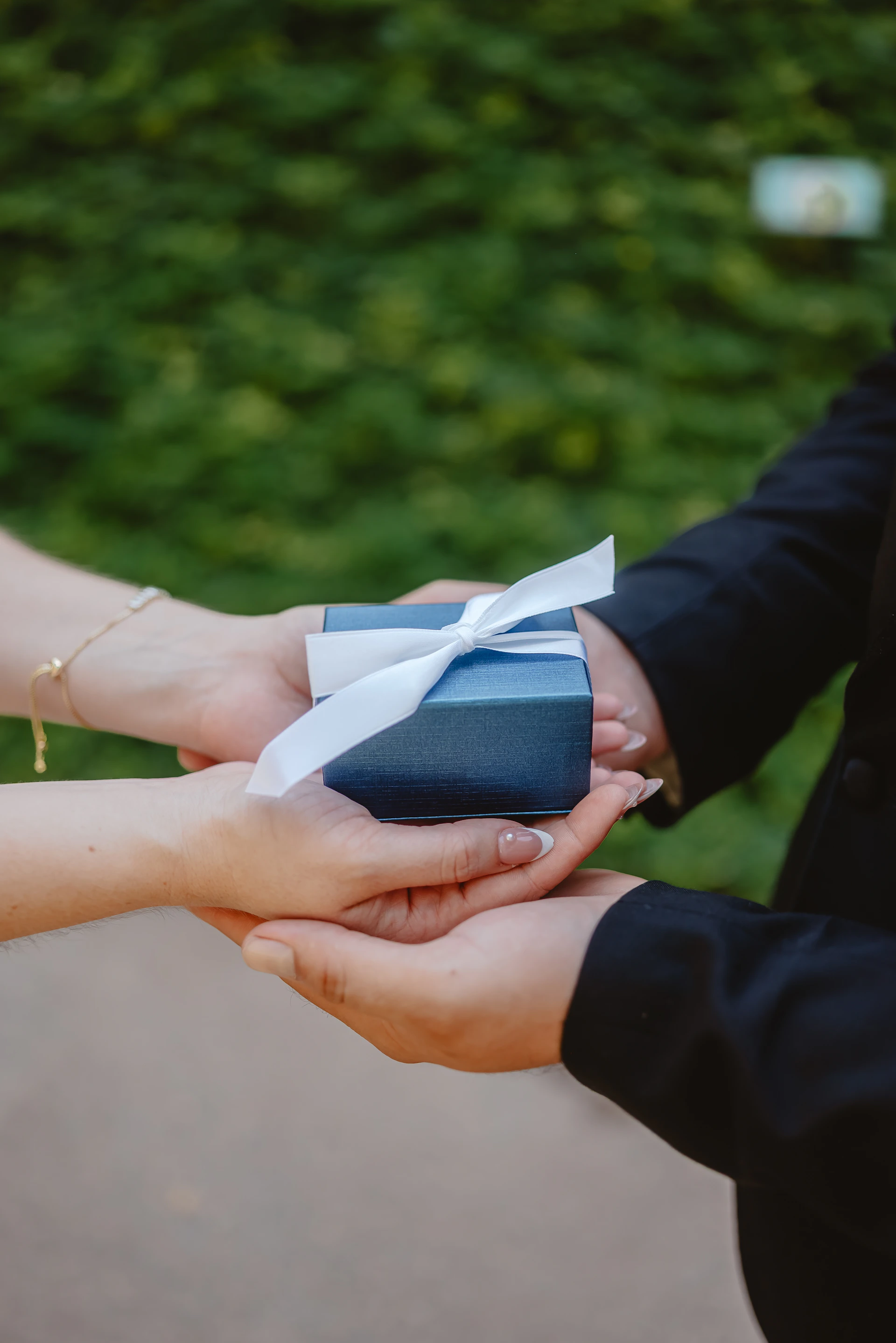 A hand giving a blue gift box to another hand