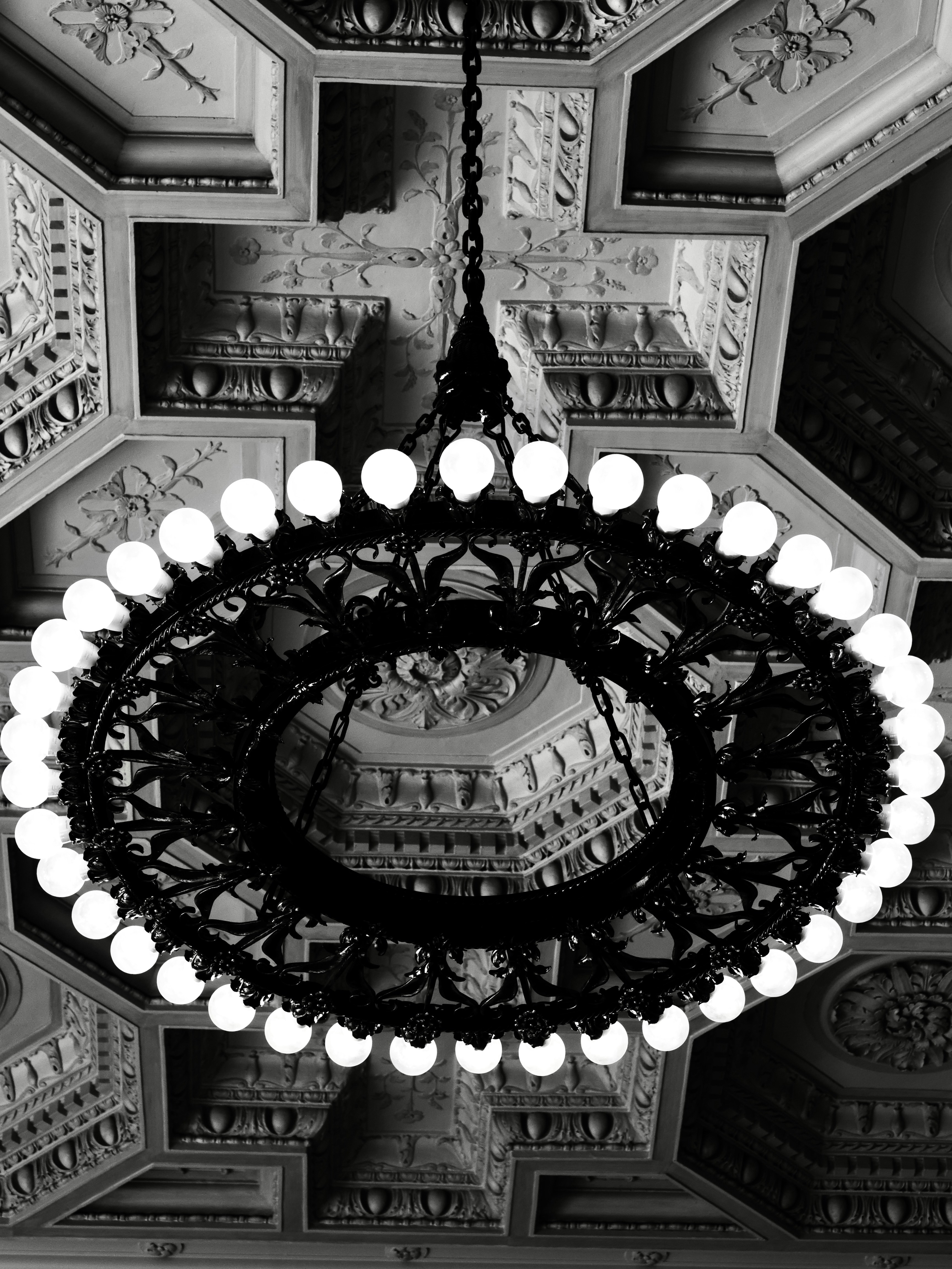 Ein kunstvoller Kronleuchter hängt von einer detaillierten Decke.