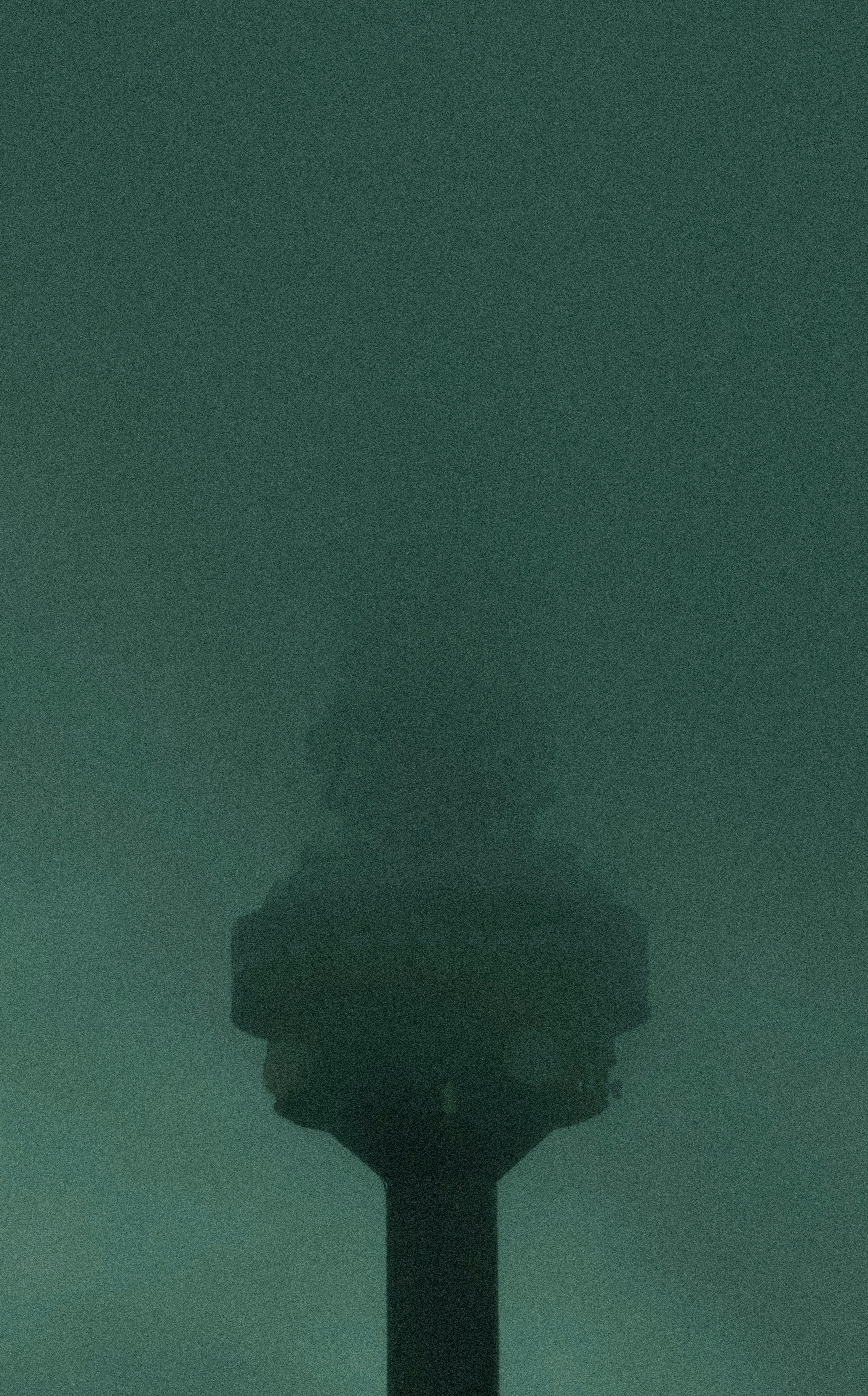 A dark silhouette of a tower emerges from fog.