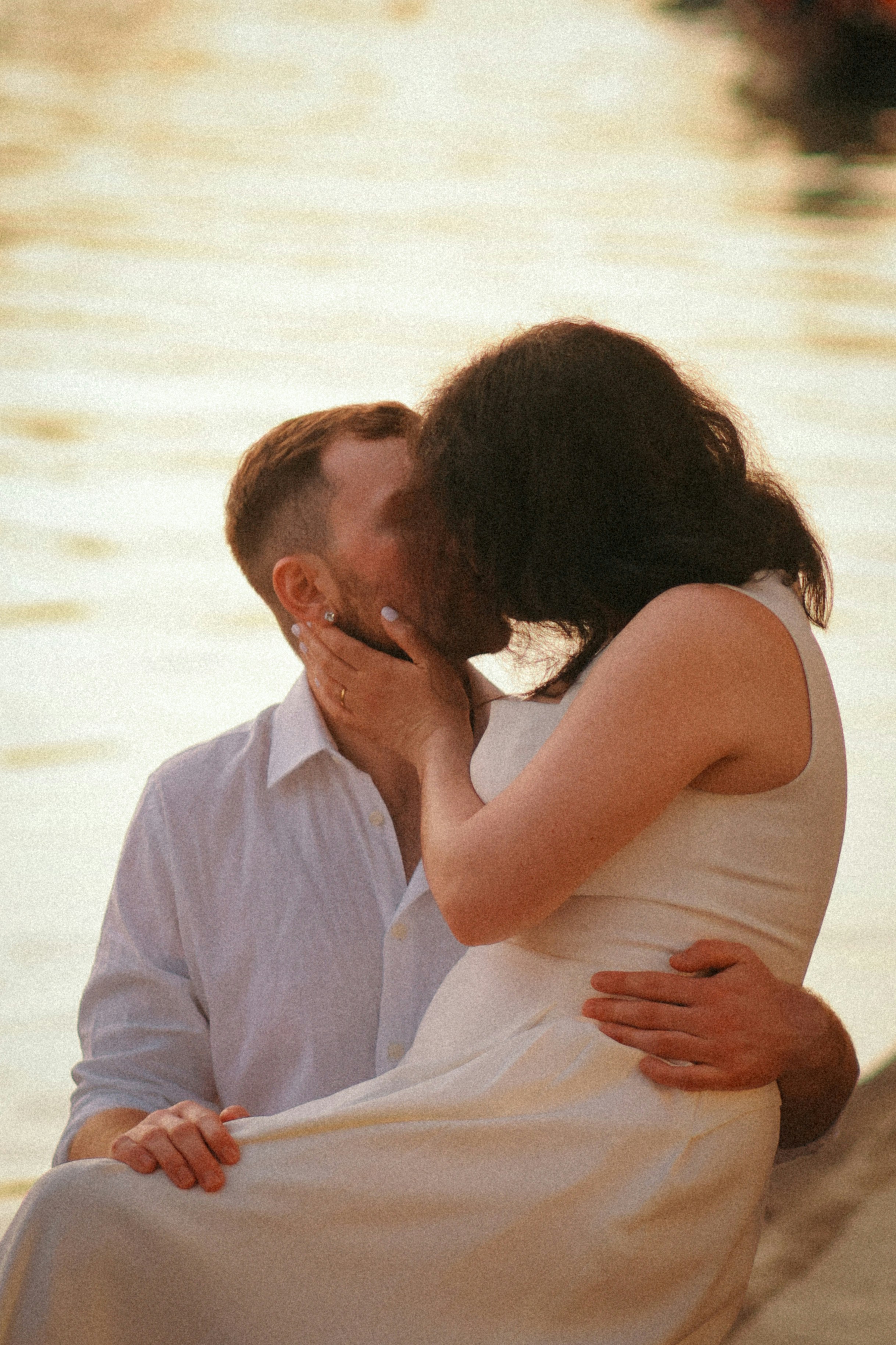 Couple kissing by the water at sunset