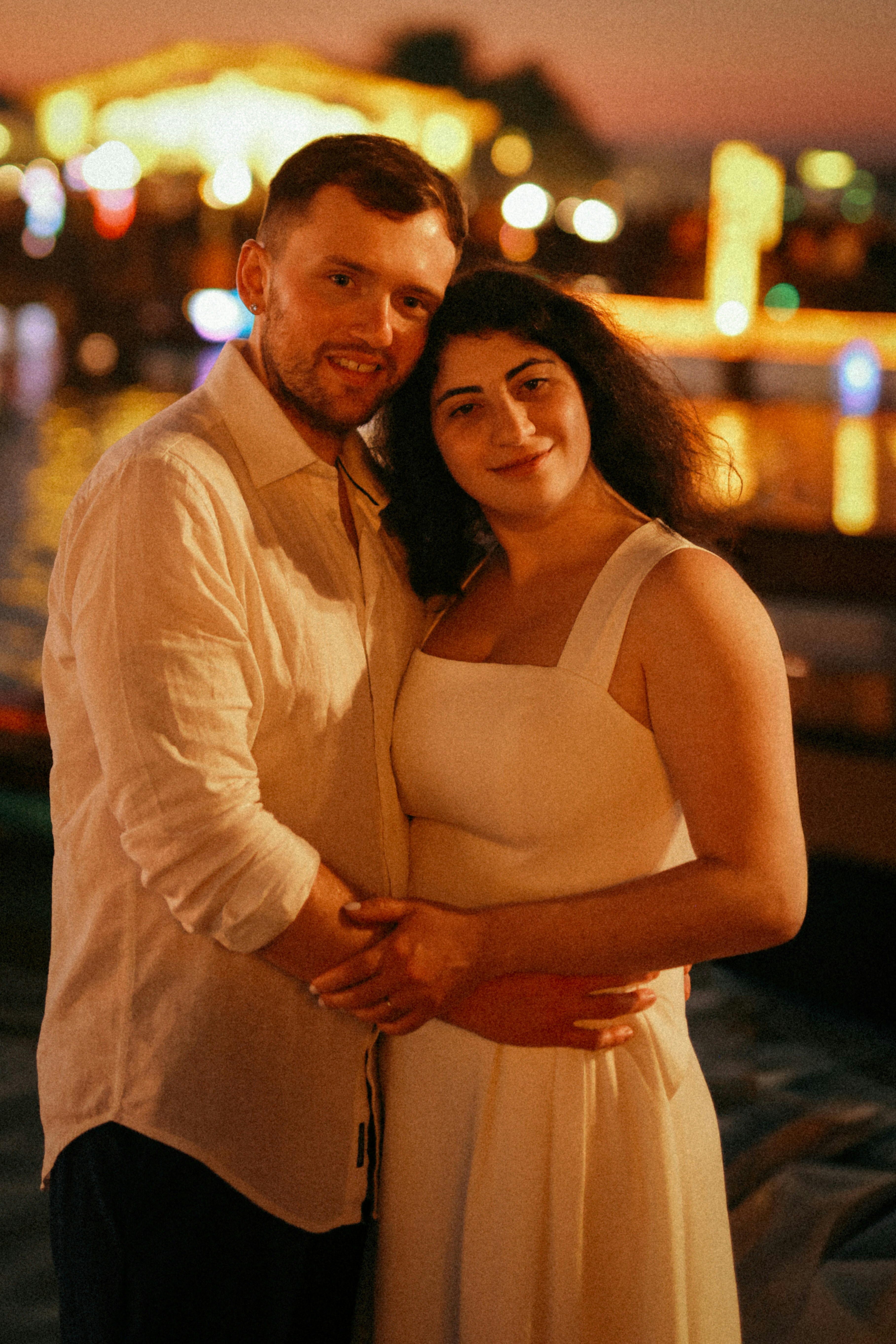 A couple poses for a photo at night.