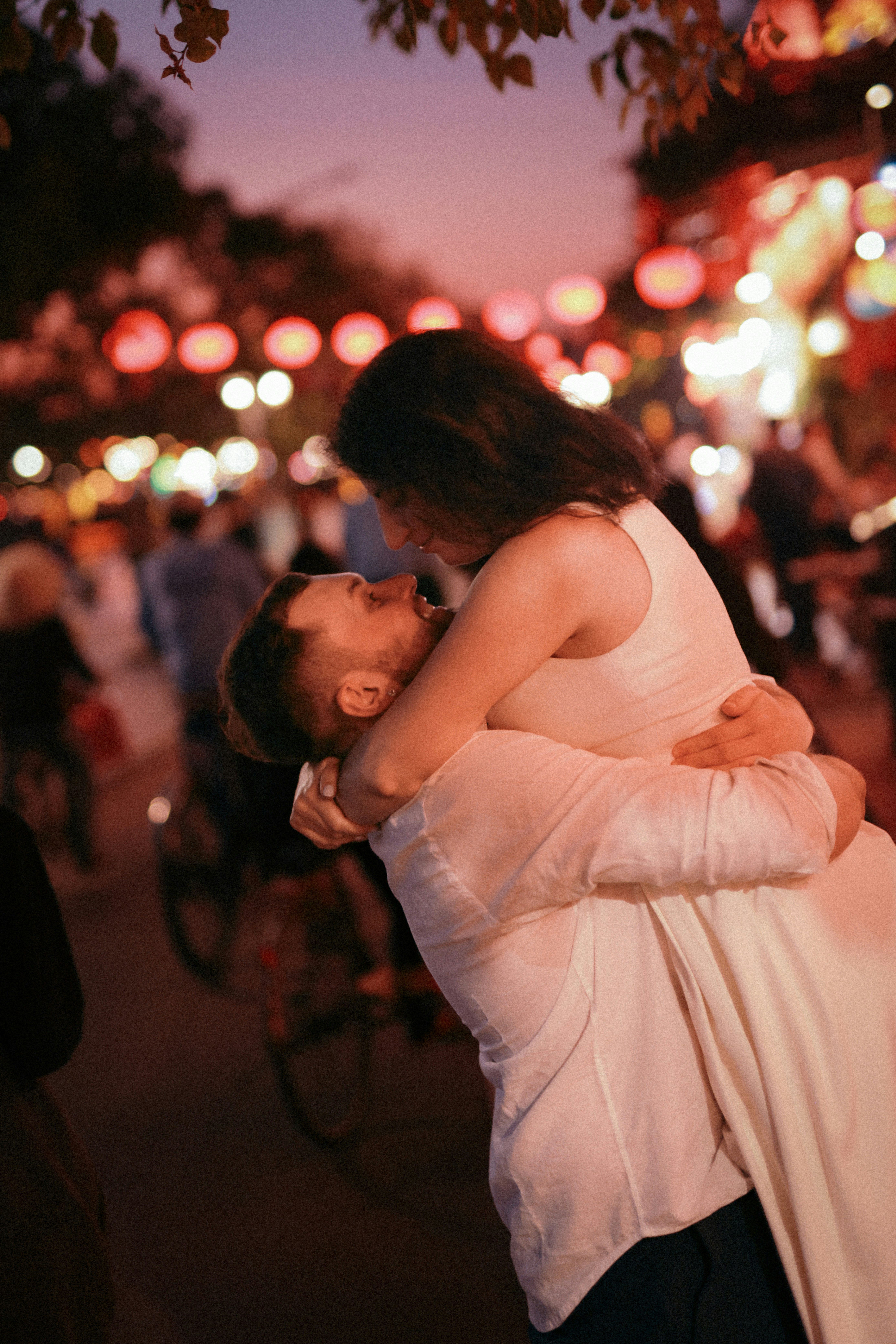 Couple embracing under illuminated lanterns at dusk