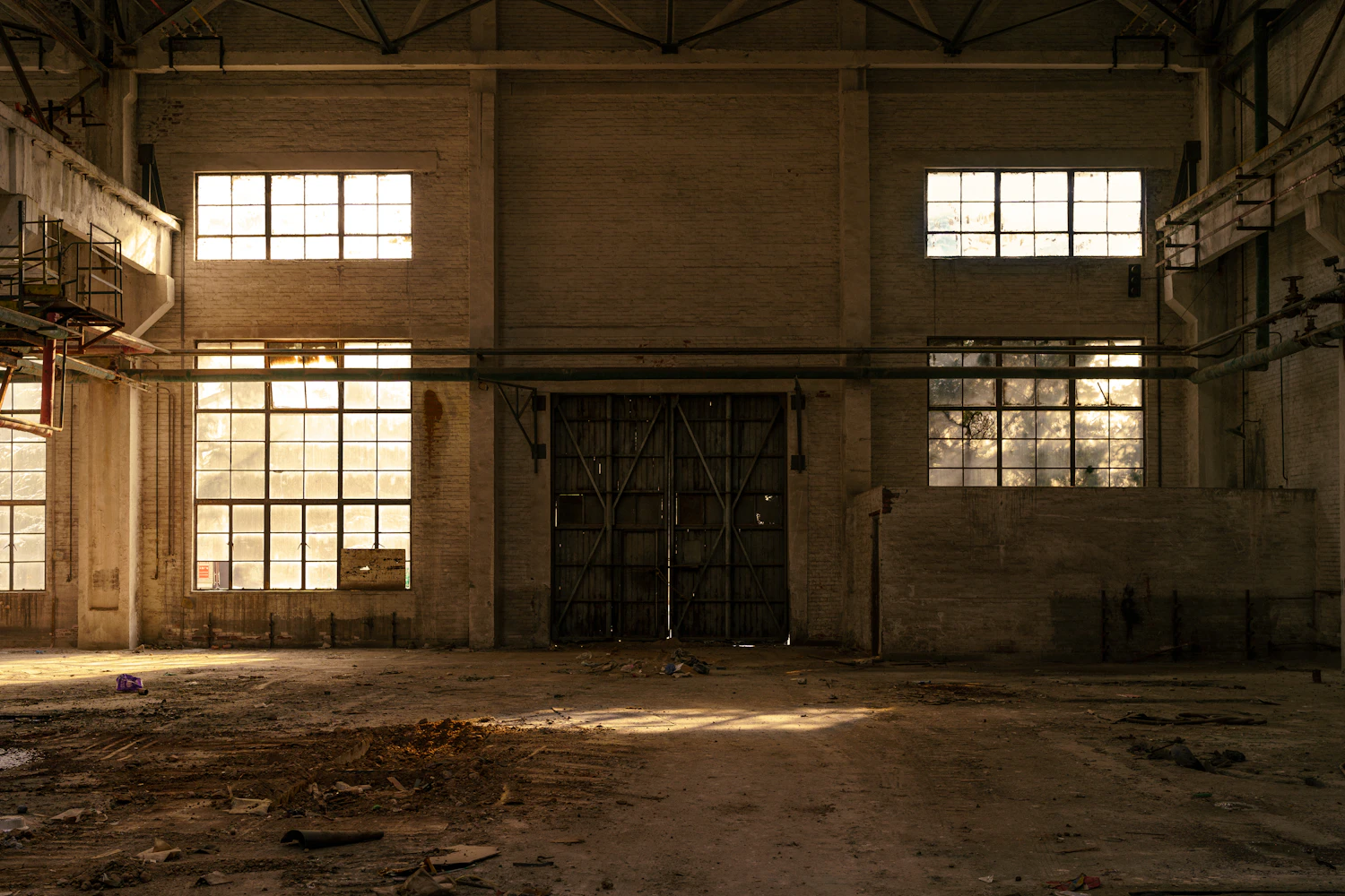 A long disused industrial hall with tall windows down one side and a bare swept floor