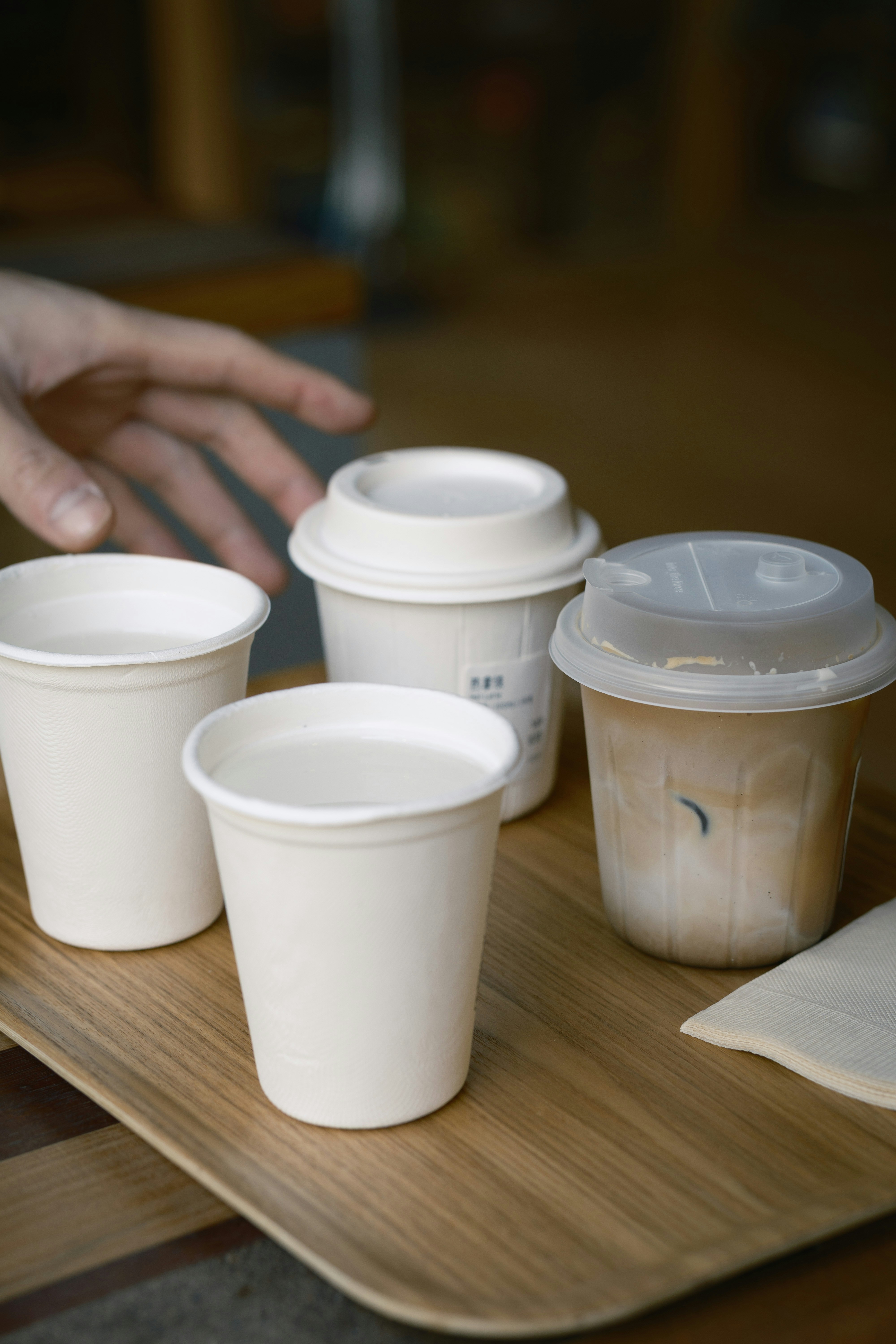 Four cups of drinks on a wooden tray.
