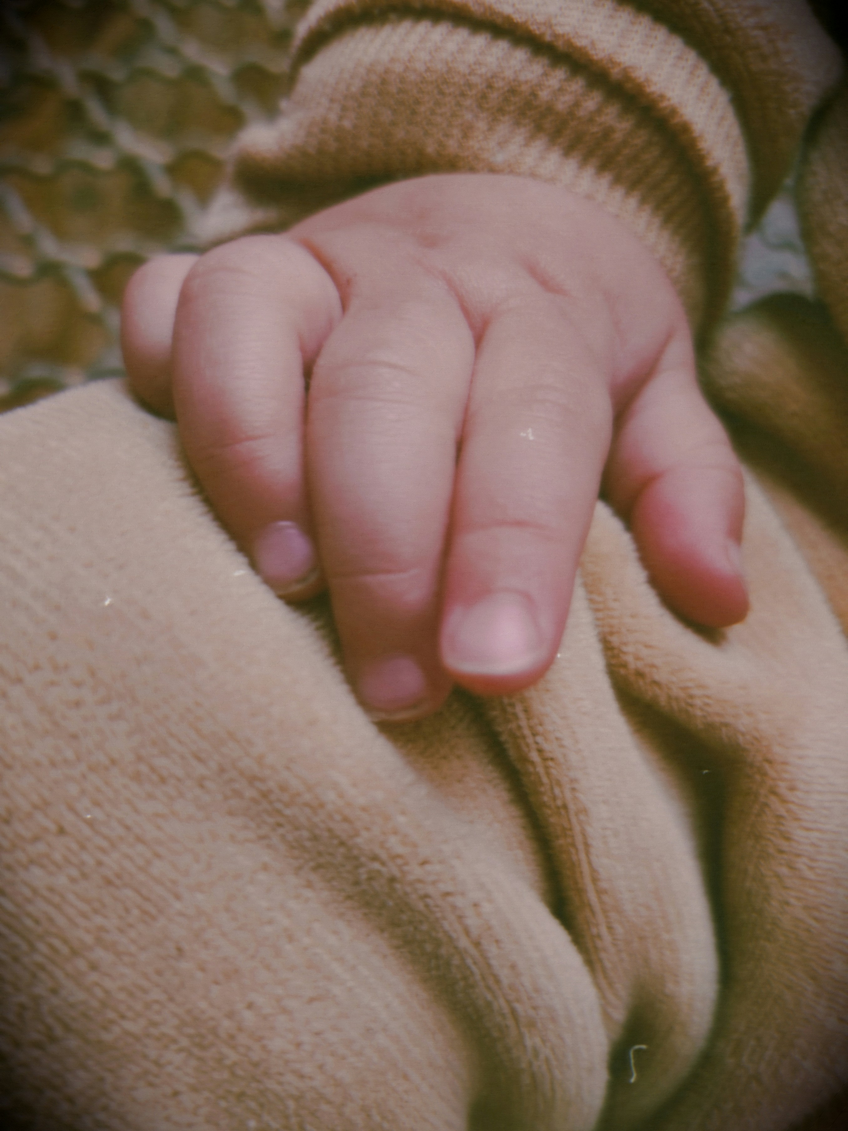 A baby's hand rests on soft fabric