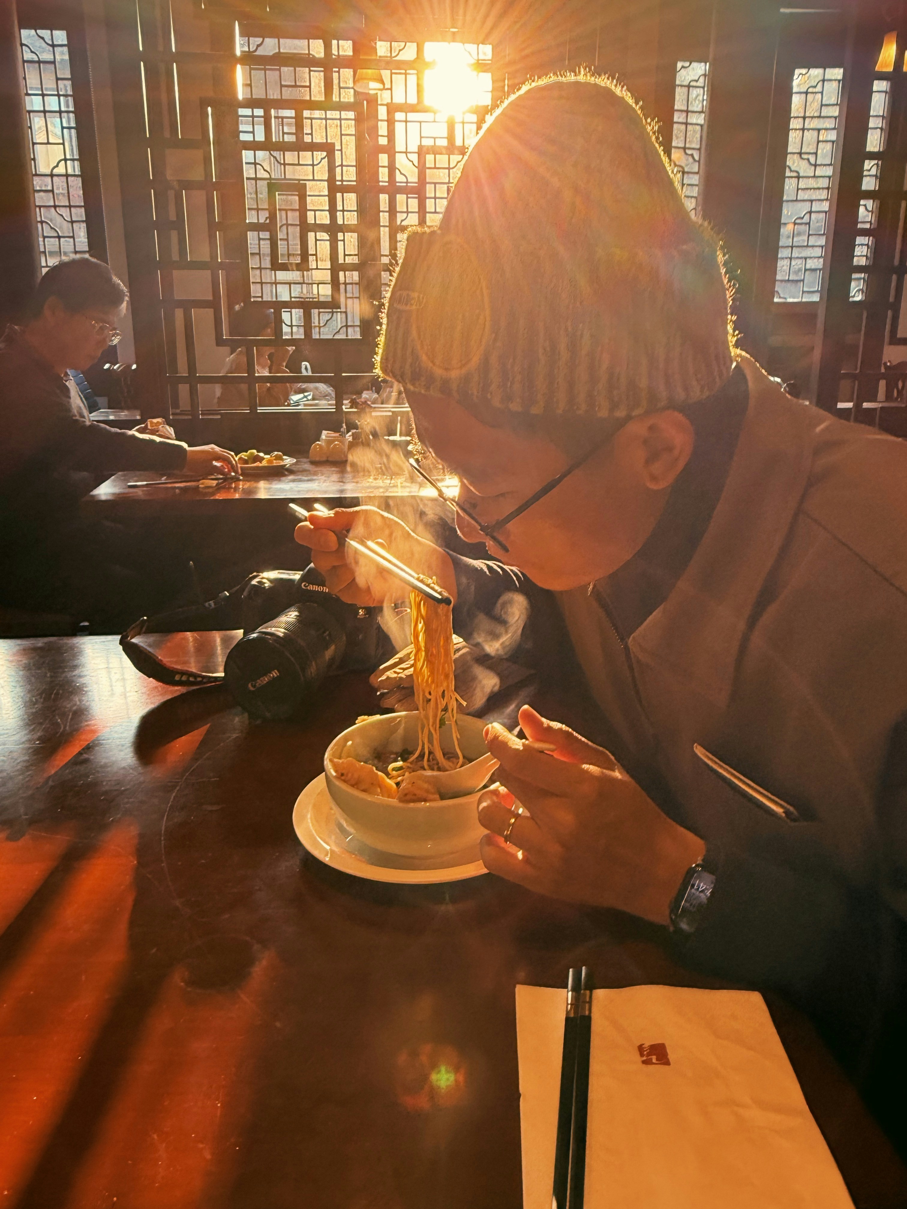 Person eating steaming noodles in a restaurant
