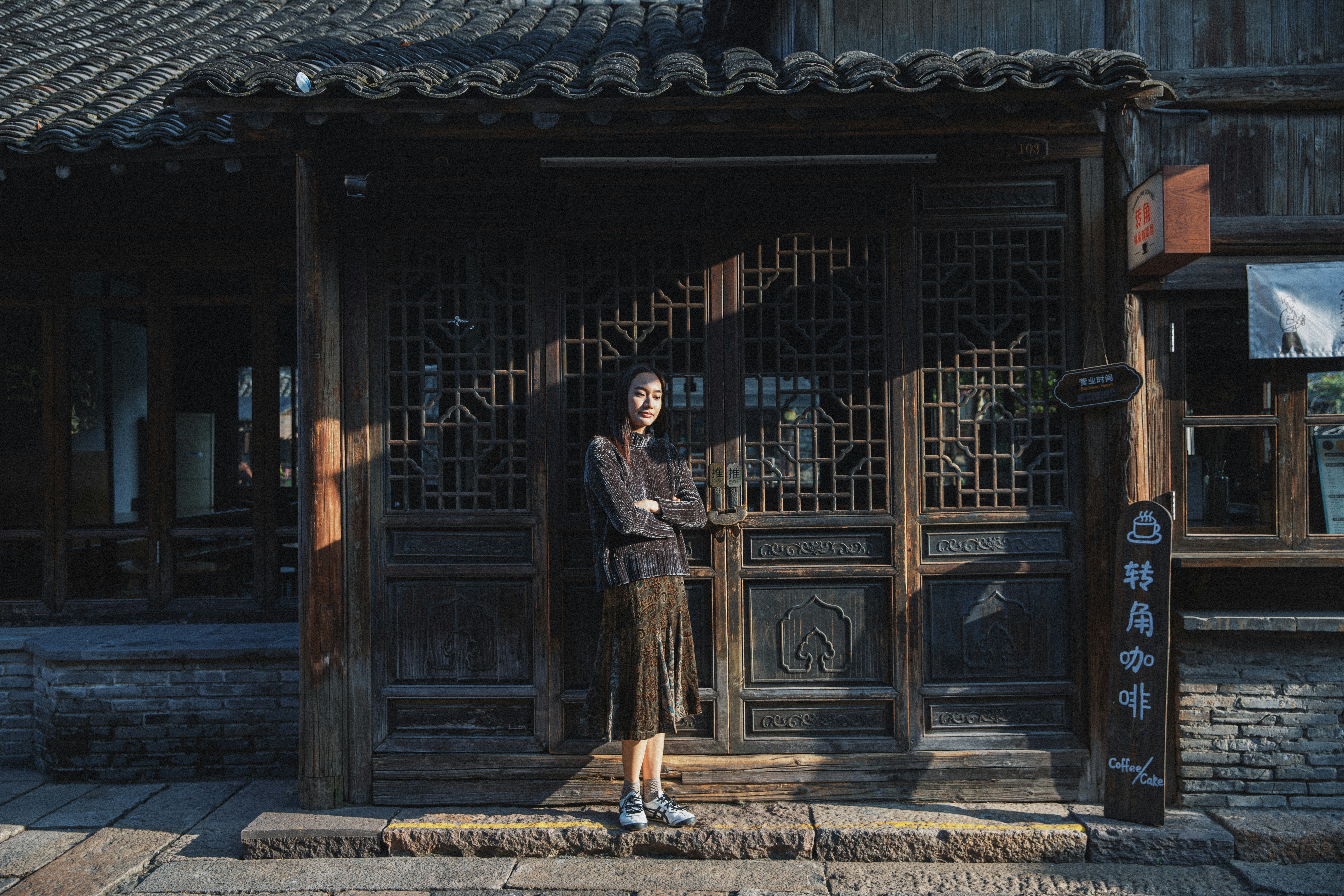 Woman standing in front of ornate wooden doorway