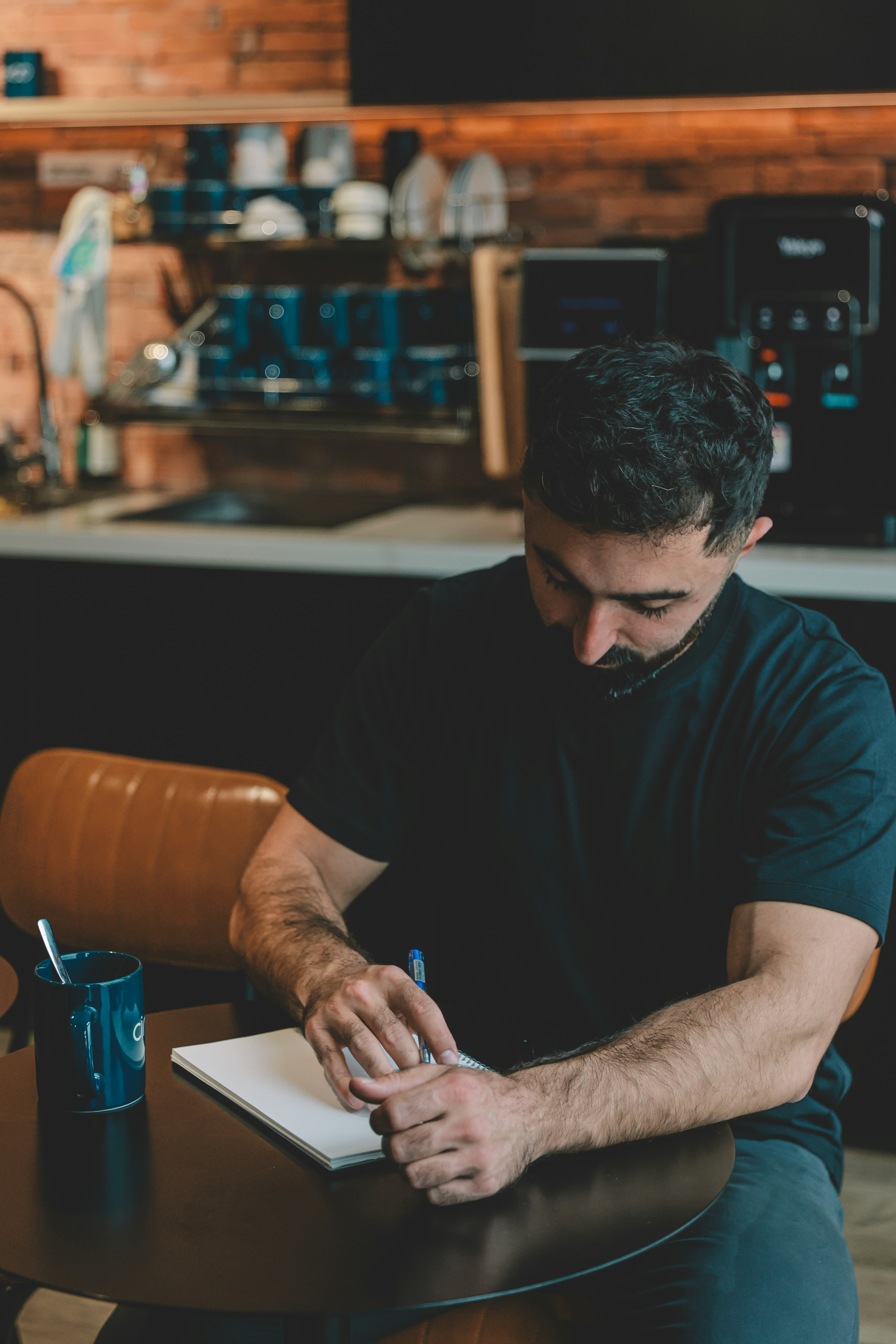 Man writing in a notebook at a table.