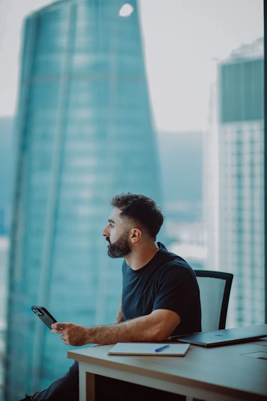 Man looking out window with phone in hand
