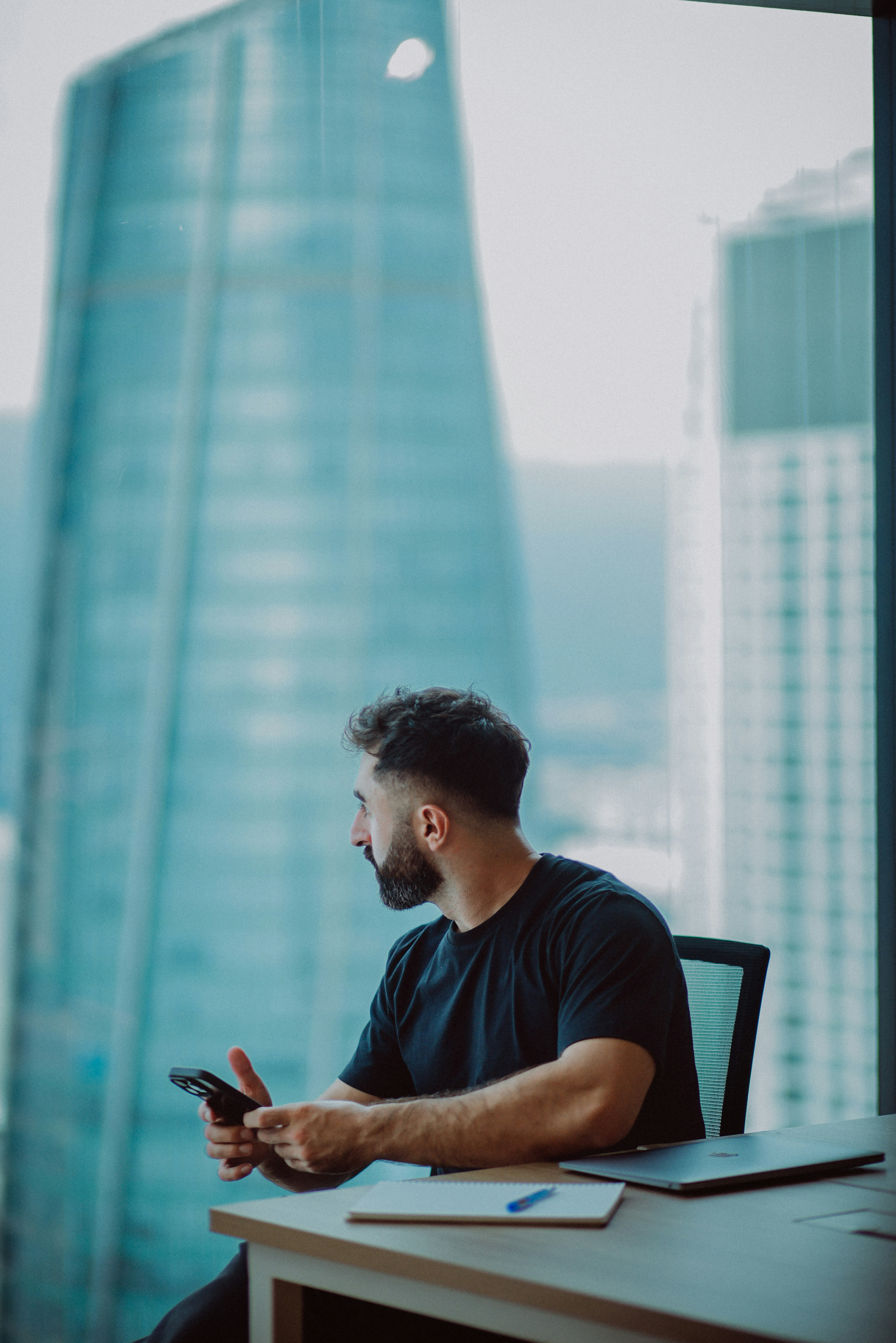 Man looking out office window at city buildings