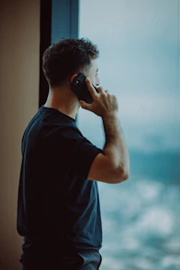 Man talking on phone looking out window