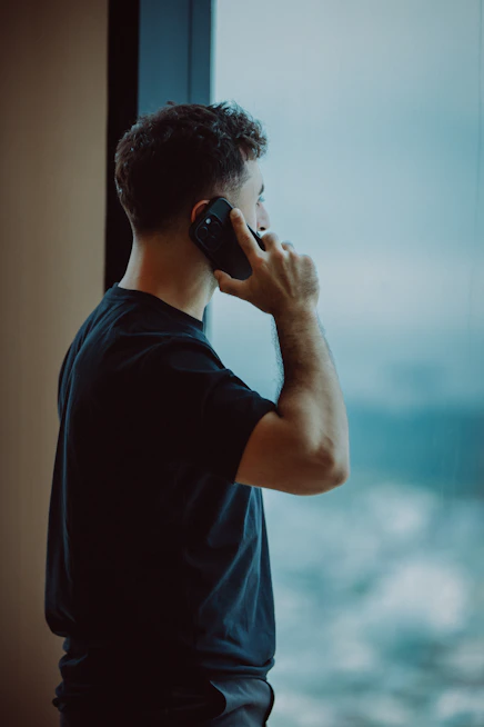 Man talking on phone looking out window
