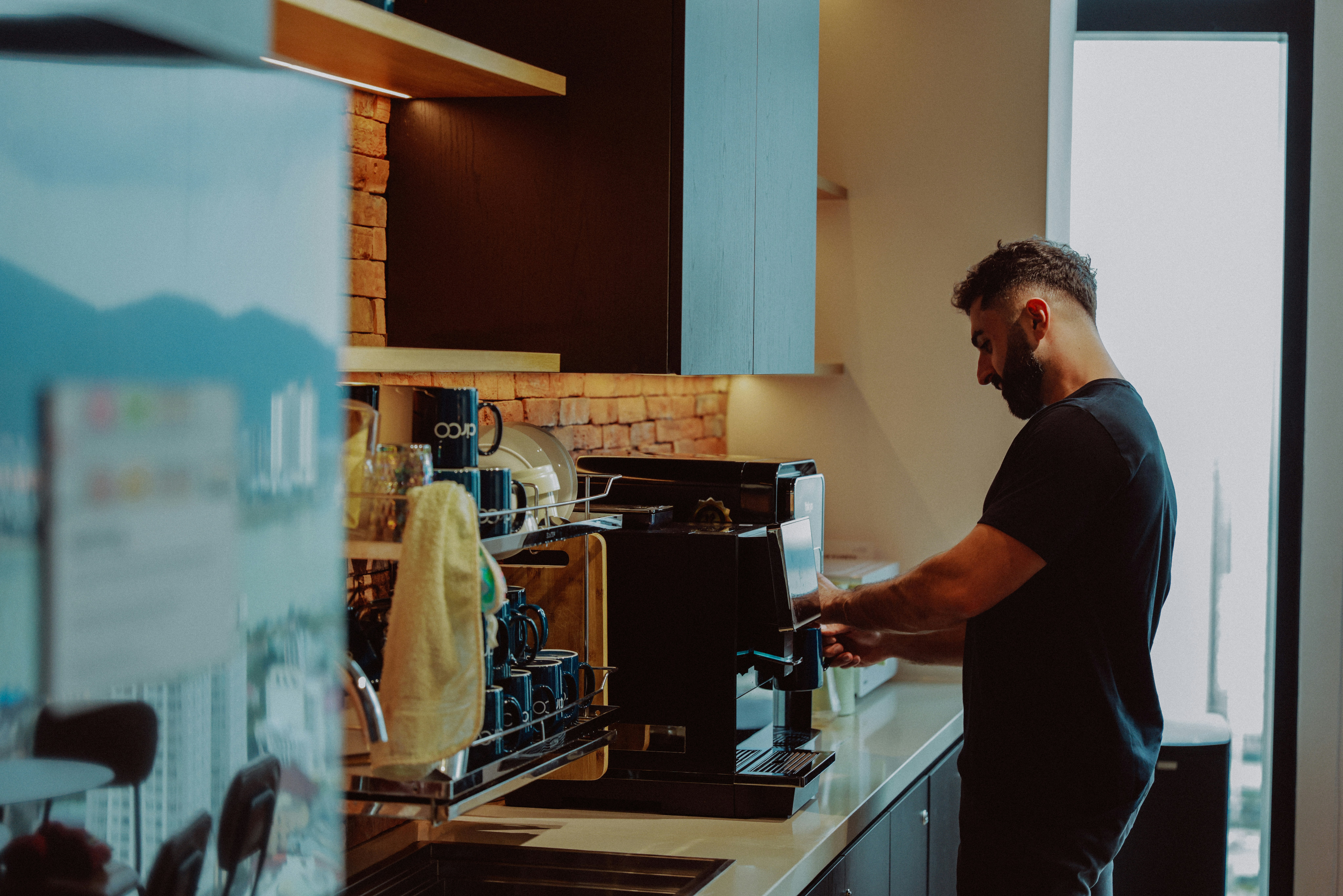 Un homme qui prépare du café avec une machine à espresso dans la cuisine.