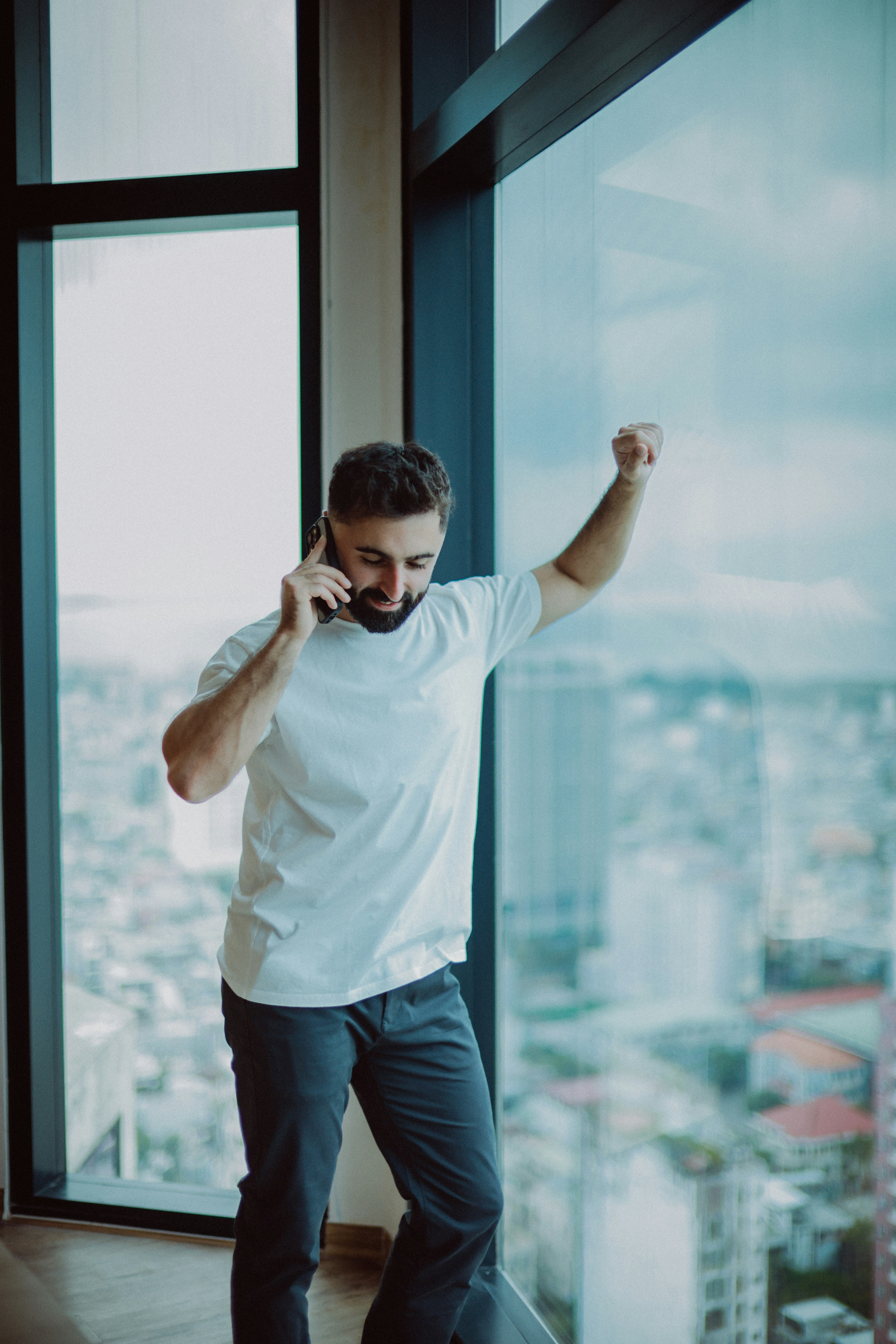Man on phone by large window with city view