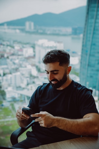 Man with beard using smartphone by the window