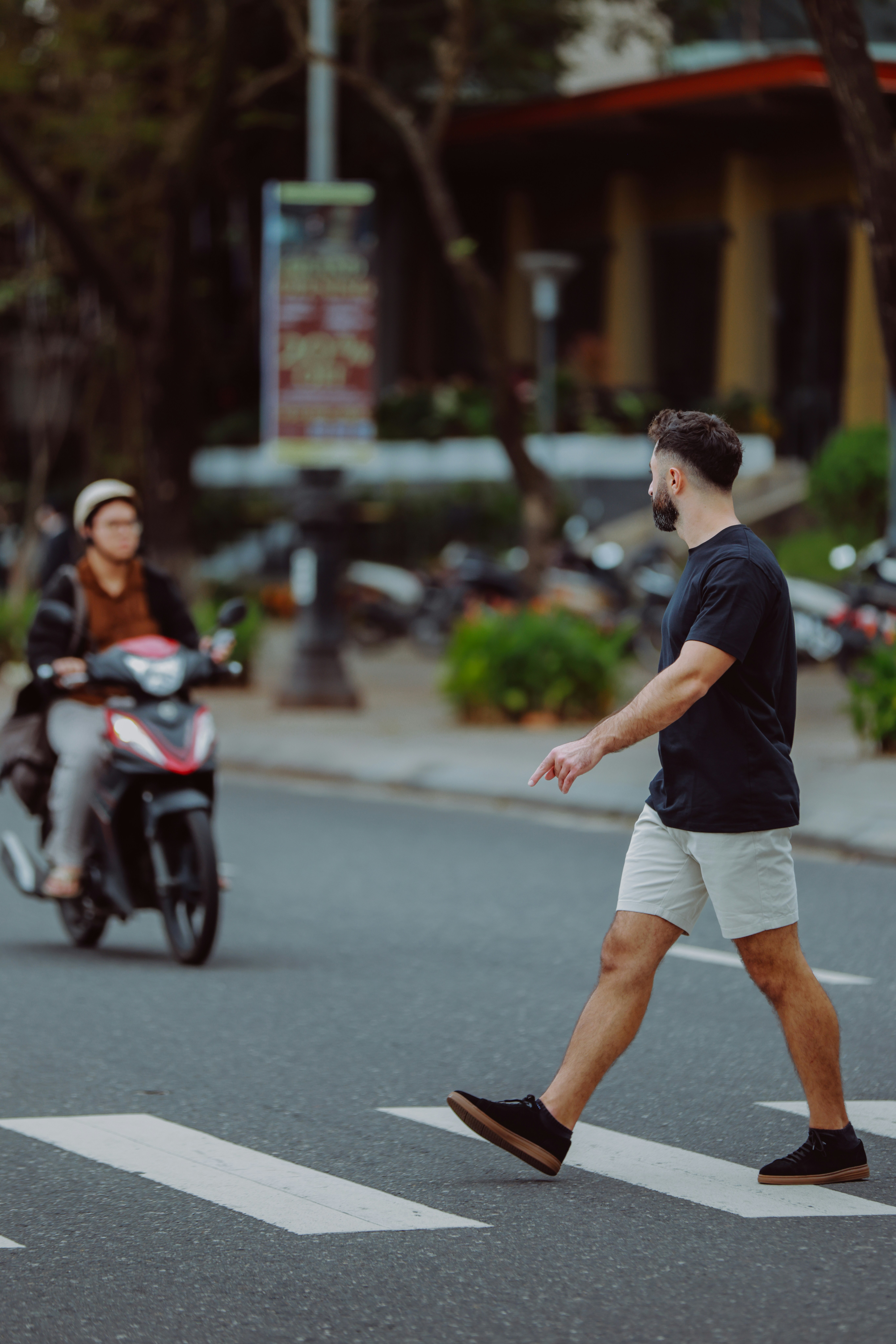 Hombre cruzando la calle por el paso de cebra, scooter acercándose ...