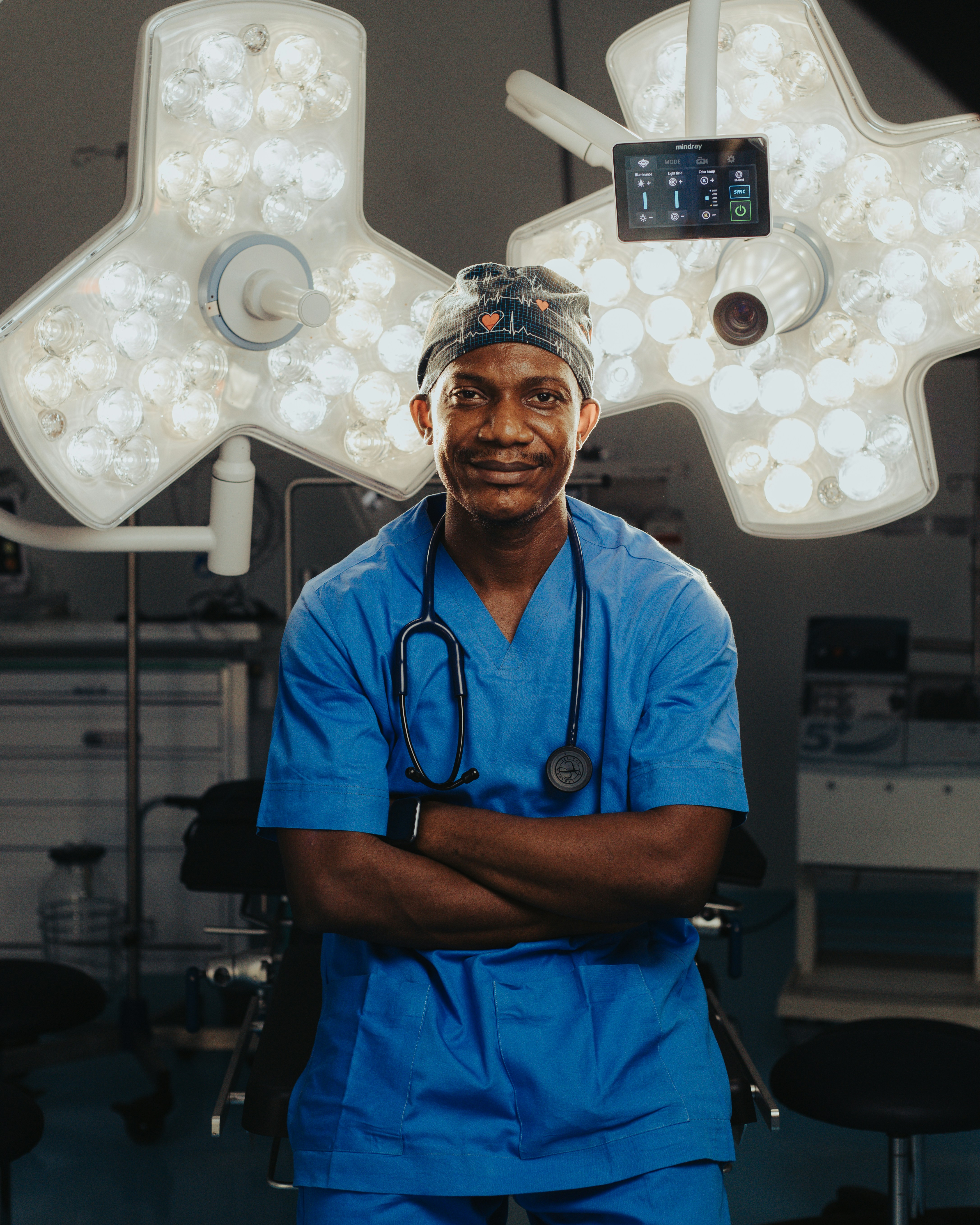 A surgeon in blue scrubs stands in an operating room.