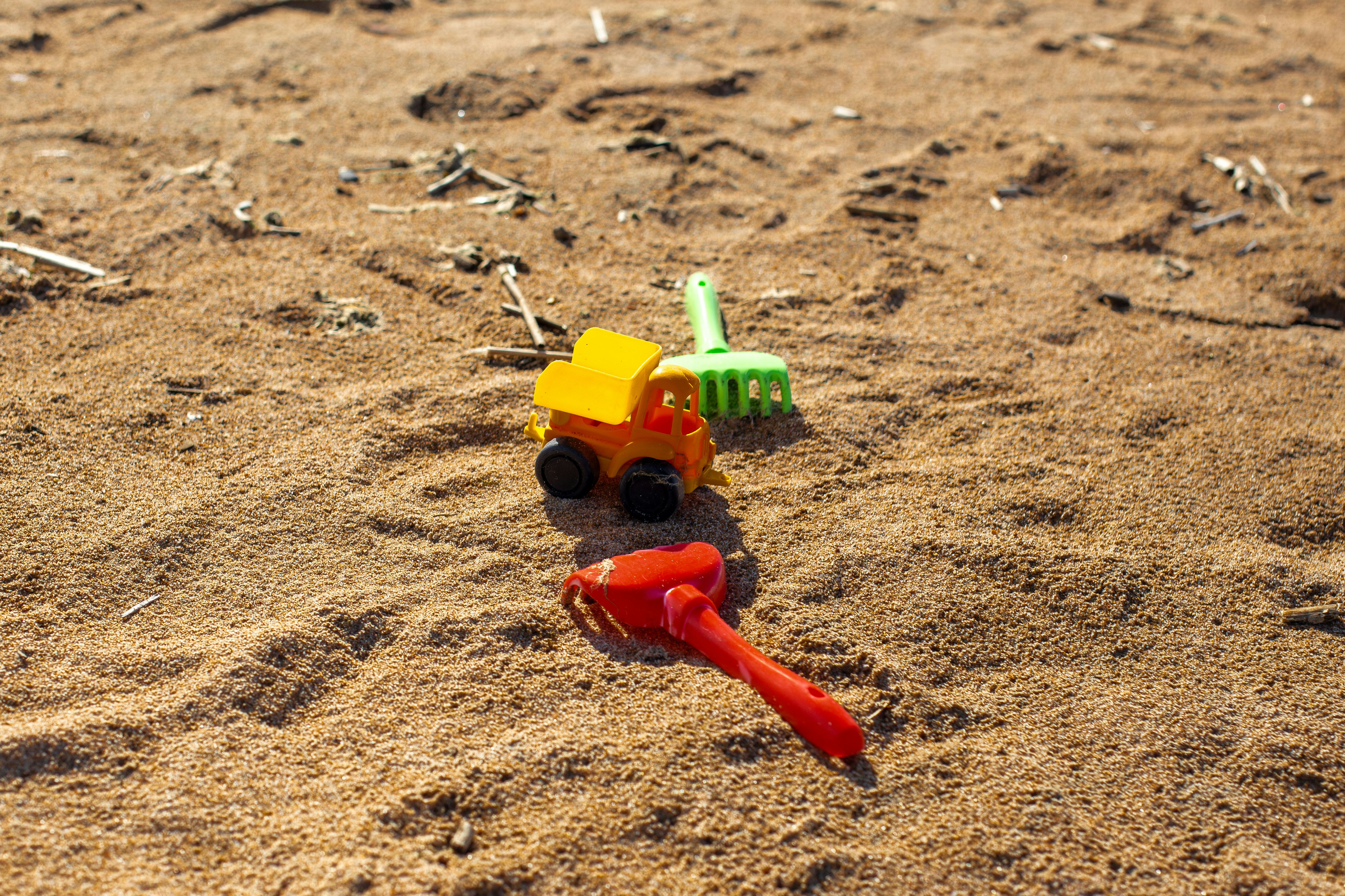 Toy truck and tools on sandy beach.