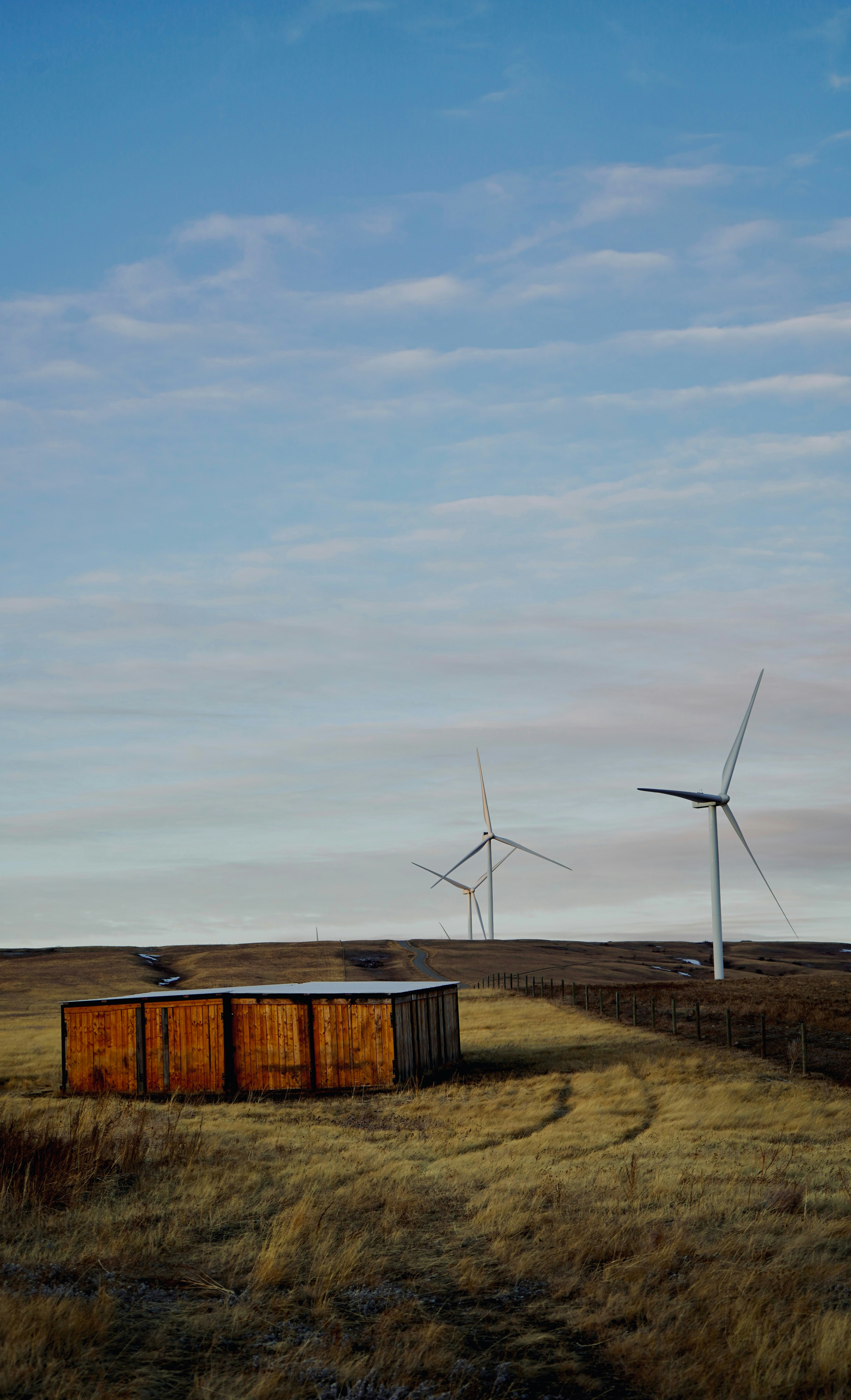 Holzschuppen und Windturbinen auf einer grasbewachsenen Ebene.