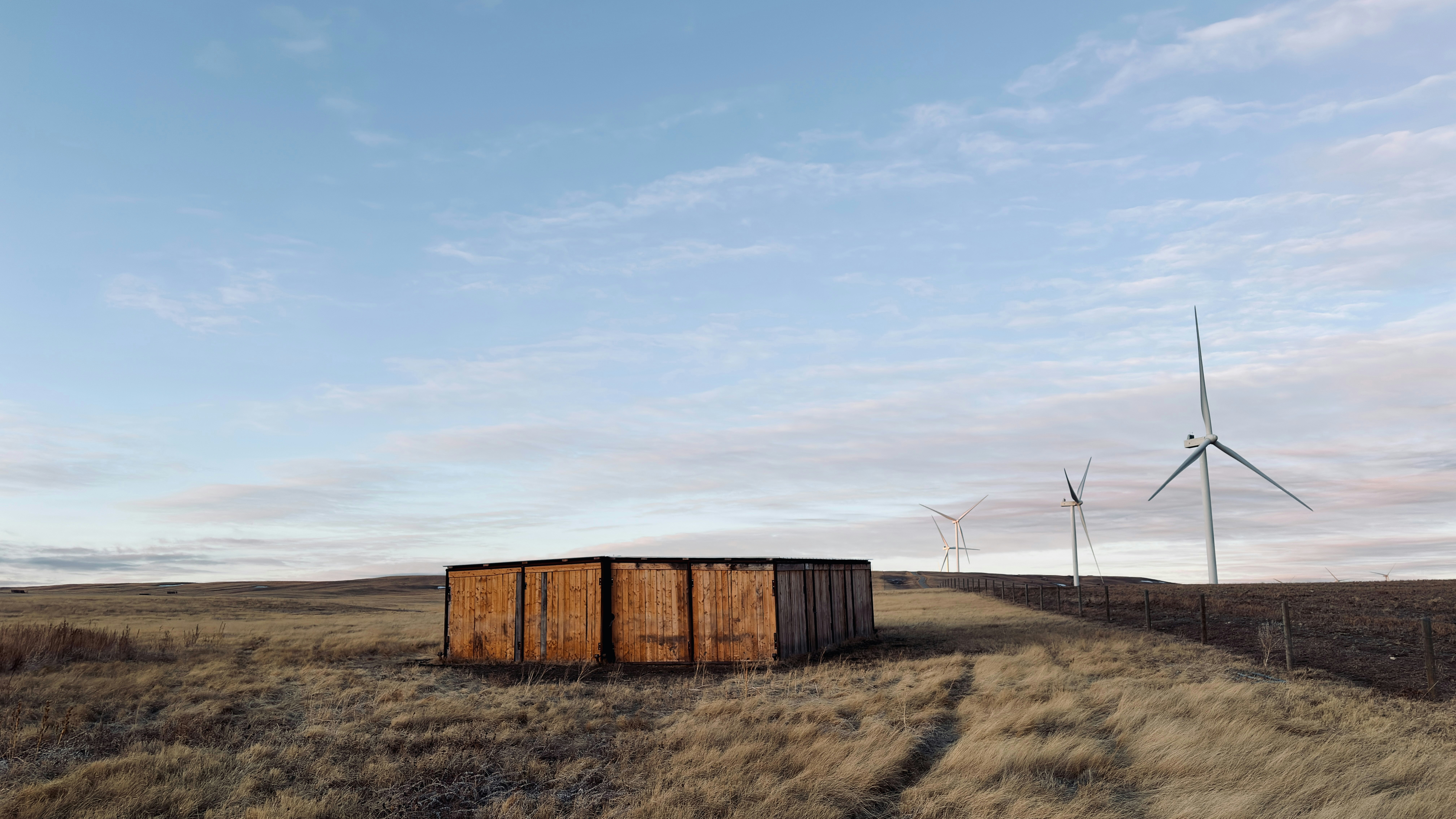 Holzkonstruktion auf einem Feld mit Windkraftanlagen.