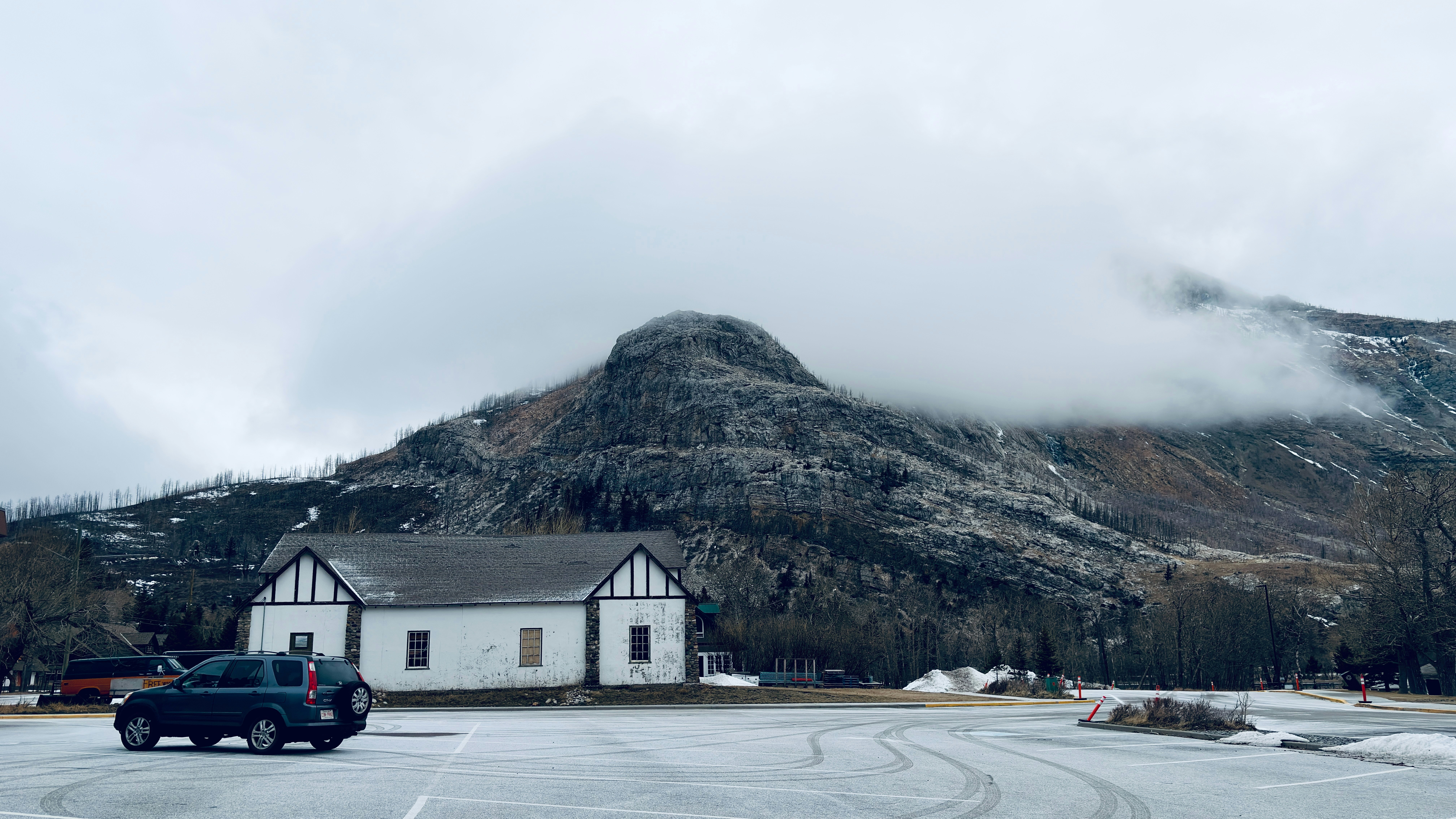 Eine verschneite Landschaft mit einem kleinen Gebäude und einem Auto.
