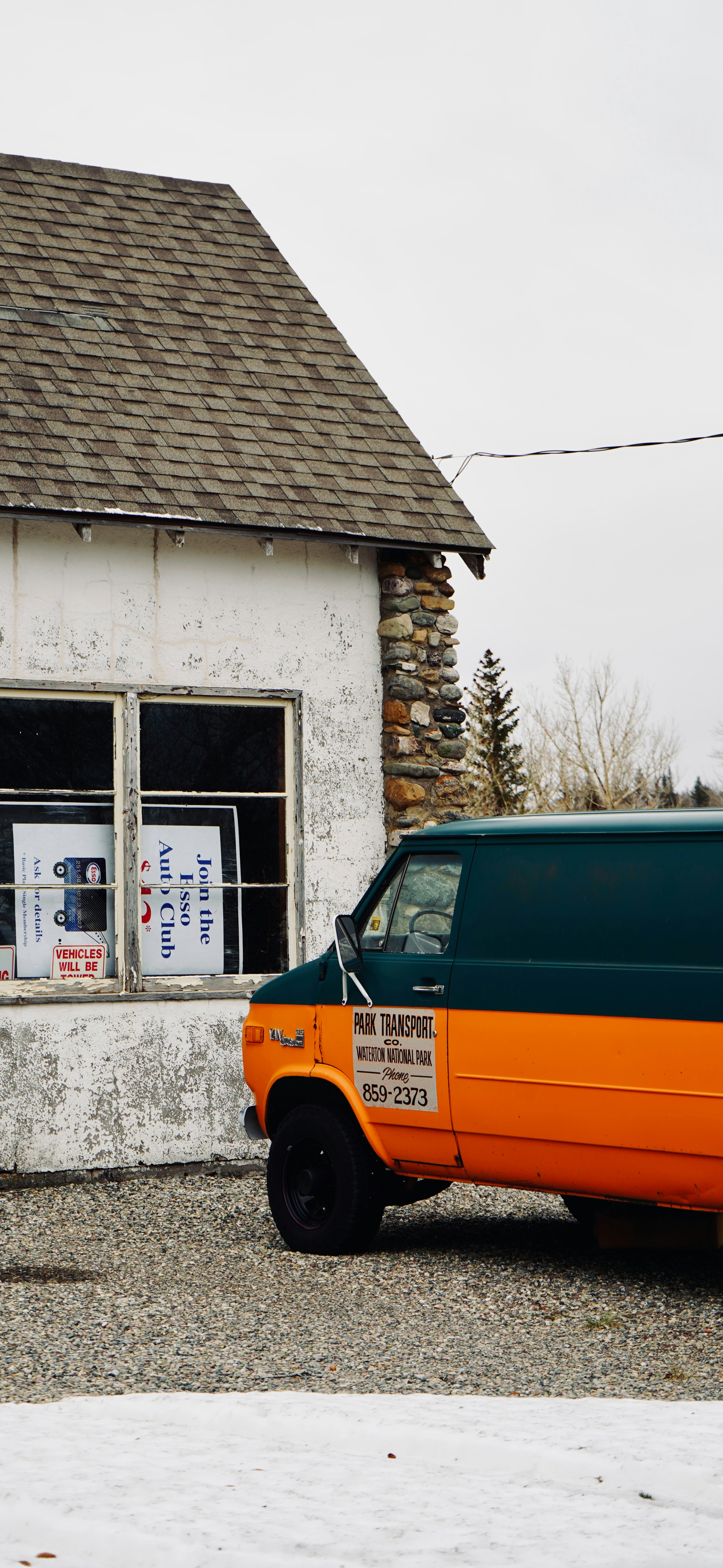 Orangefarbener und türkisfarbener Van parkt neben einem verwitterten Gebäude