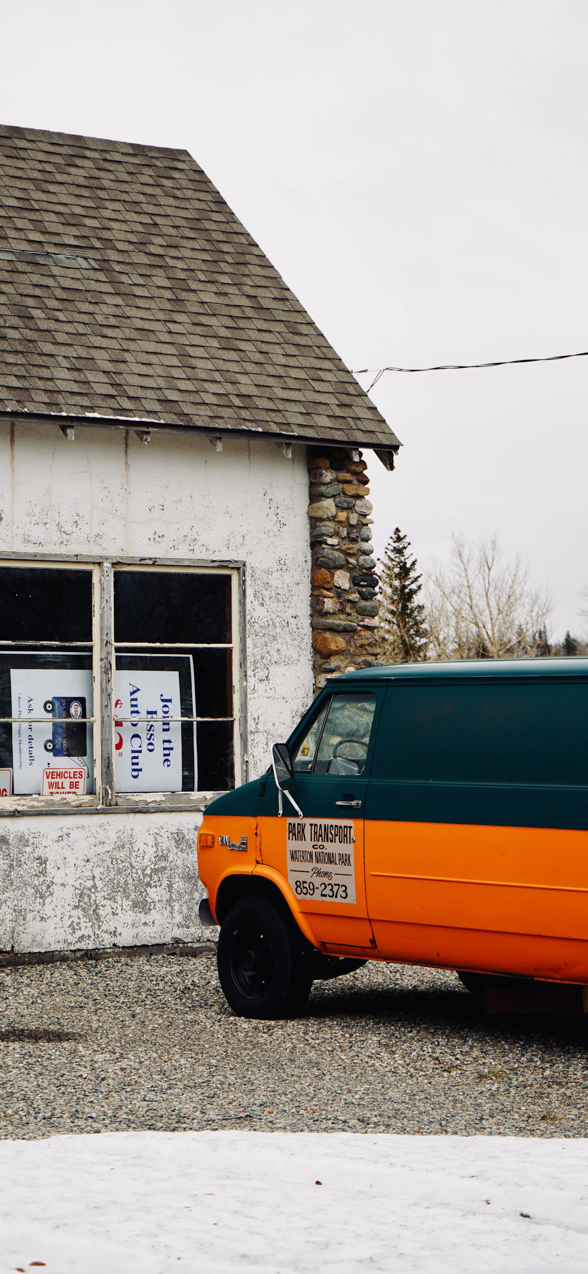 Orange and teal van parked by a weathered building